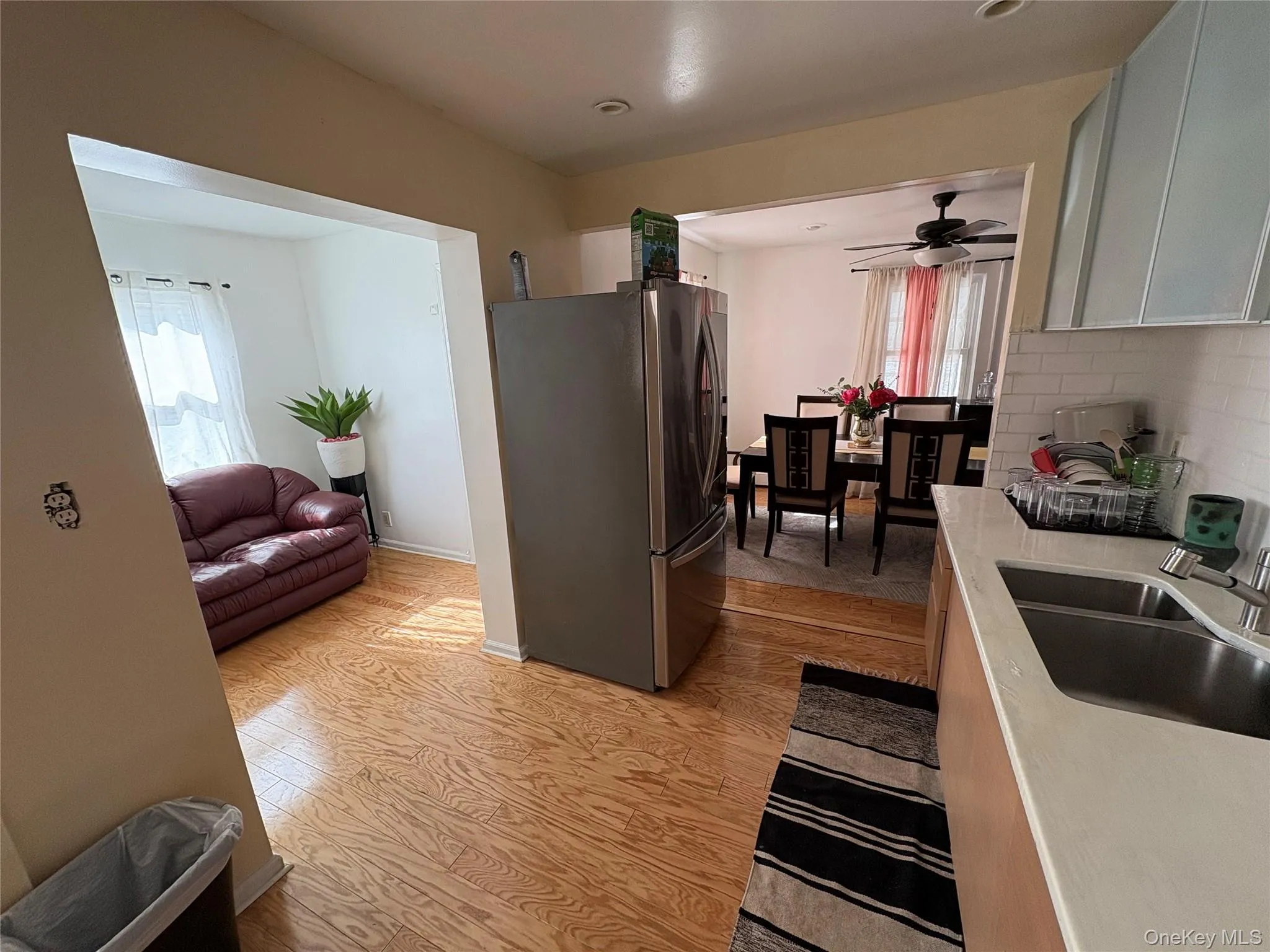 Kitchen with freestanding refrigerator, ceiling fan, tasteful backsplash, light wood-type flooring, and light countertops Kitchen with freestanding refrigerator, ceiling fan, tasteful backsplash, light wood-type flooring, and light countertops