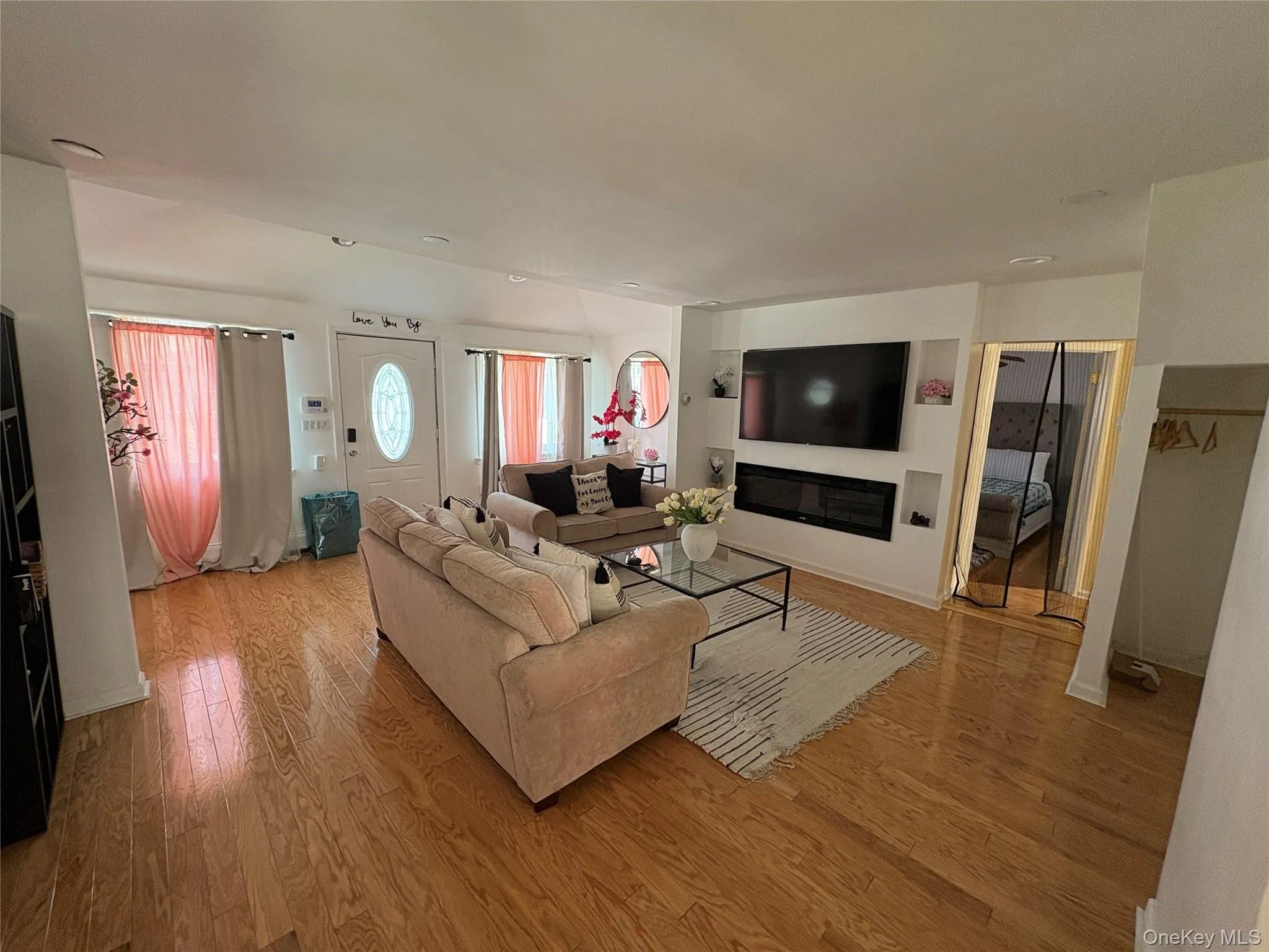 Living room with light wood-style flooring and a glass covered fireplace Living room with light wood-style flooring and a glass covered fireplace