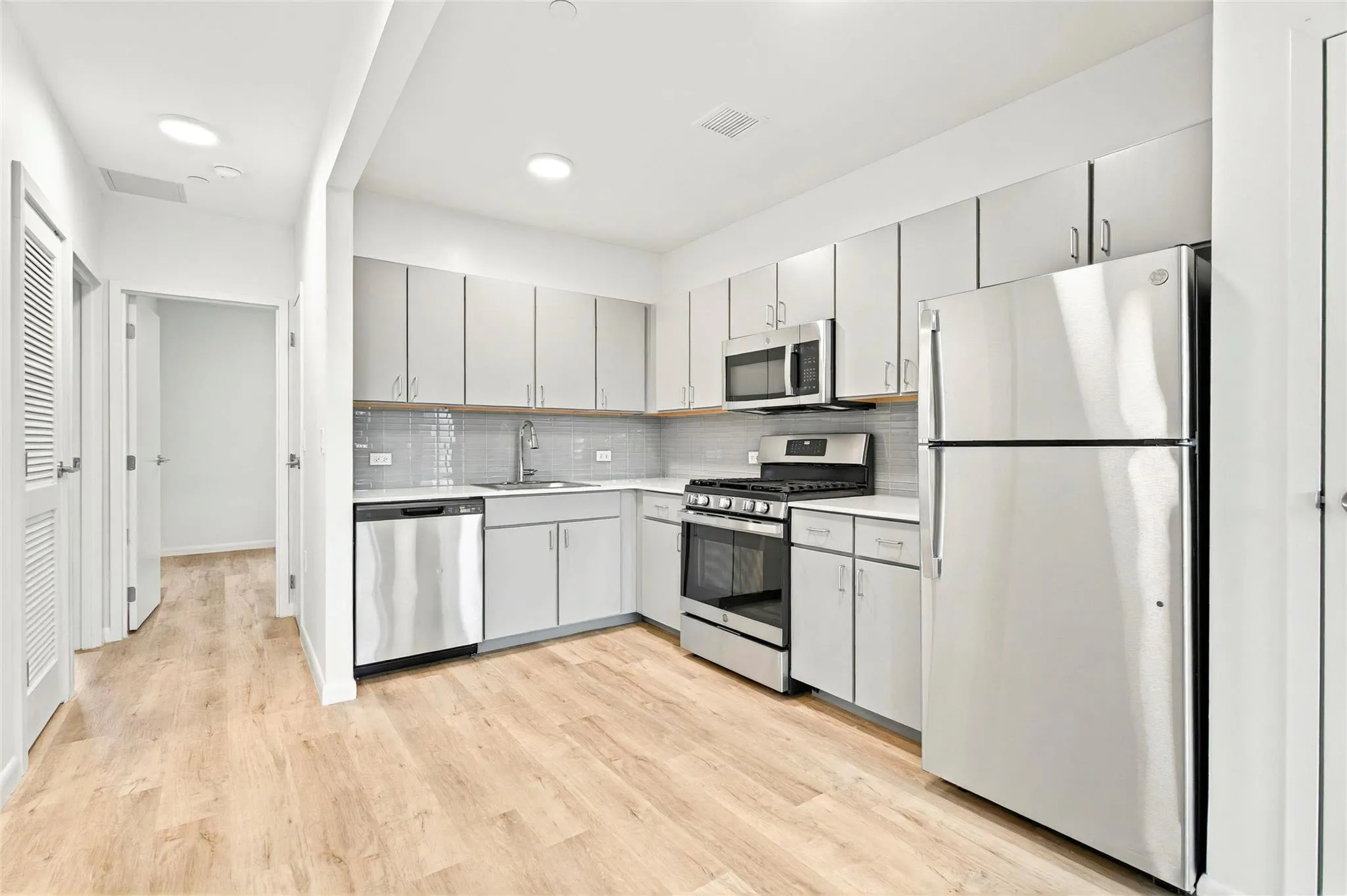 Kitchen showing stainless steel refrigerator, stove, microwave and dishwasher and hallway to the bedrooms Kitchen showing stainless steel refrigerator, stove, microwave and dishwasher and hallway to the bedrooms