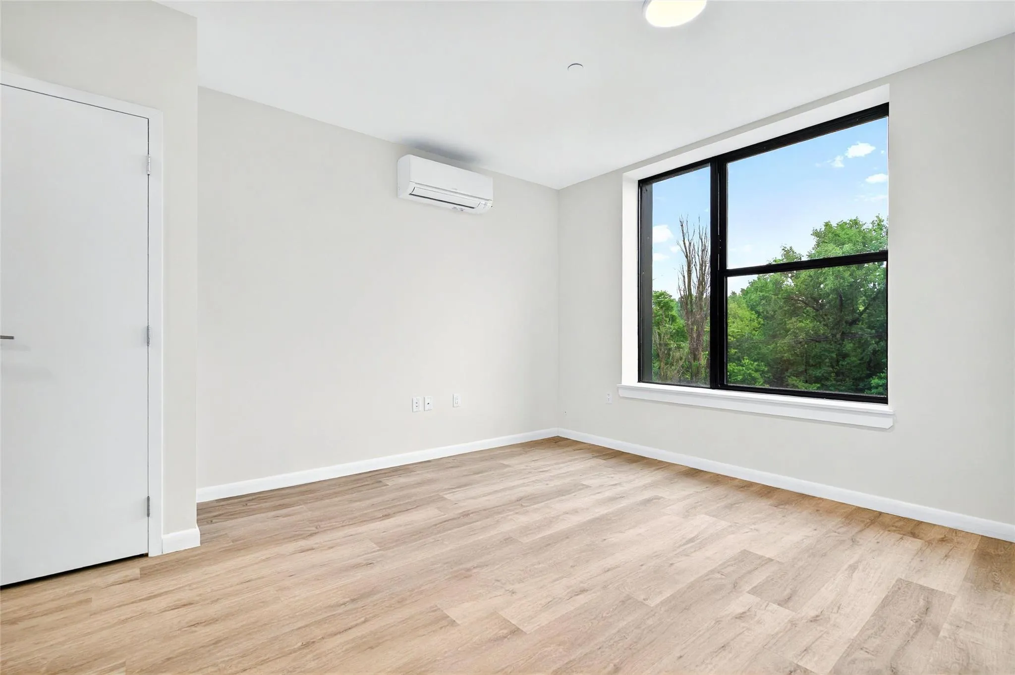 Spare room featuring a wall unit AC, light wood finished floors, and baseboards Spare room featuring a wall unit AC, light wood finished floors, and baseboards