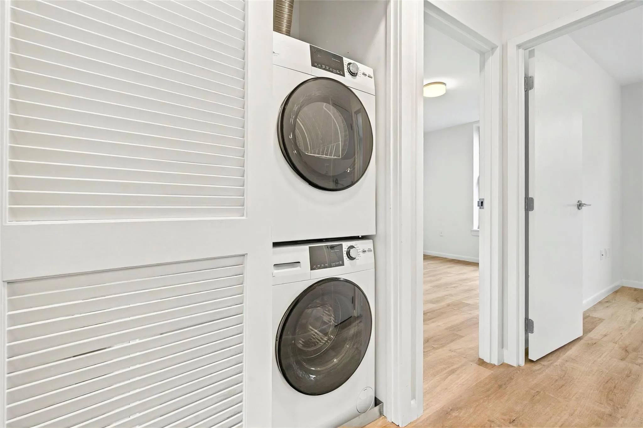 Laundry area with stacked washer / drying machine, light wood-type flooring, and baseboards Laundry area with stacked washer / drying machine, light wood-type flooring, and baseboards