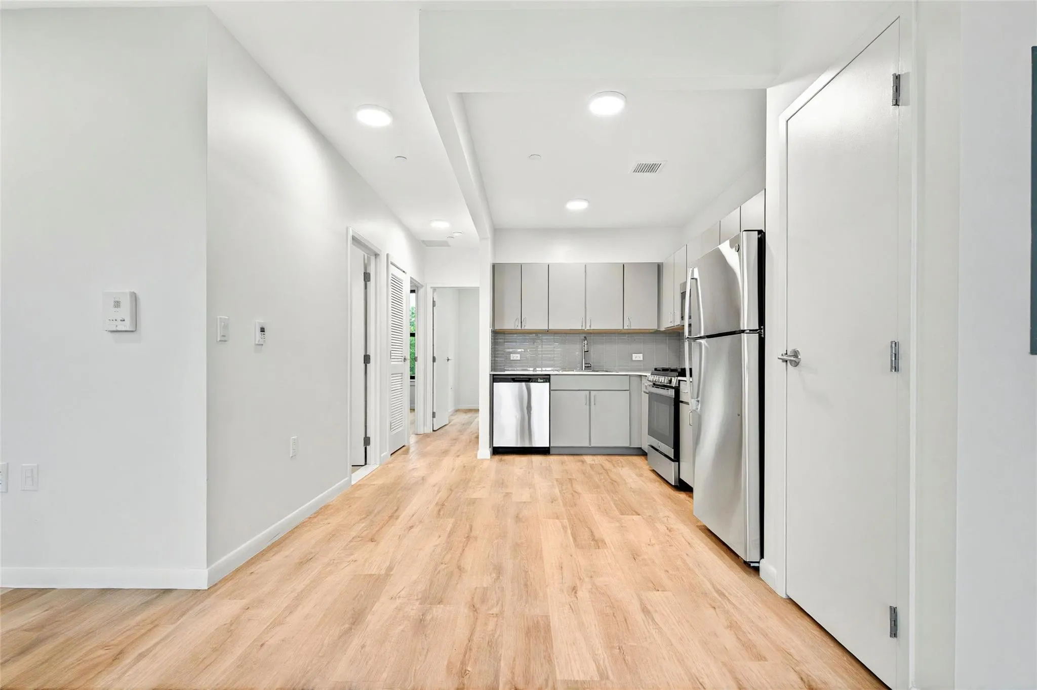 Kitchen featuring appliances with stainless steel finishes, gray cabinets, a sink, light wood-type flooring, and recessed lighting Kitchen featuring appliances with stainless steel finishes, gray cabinets, a sink, light wood-type flooring, and recessed lighting
