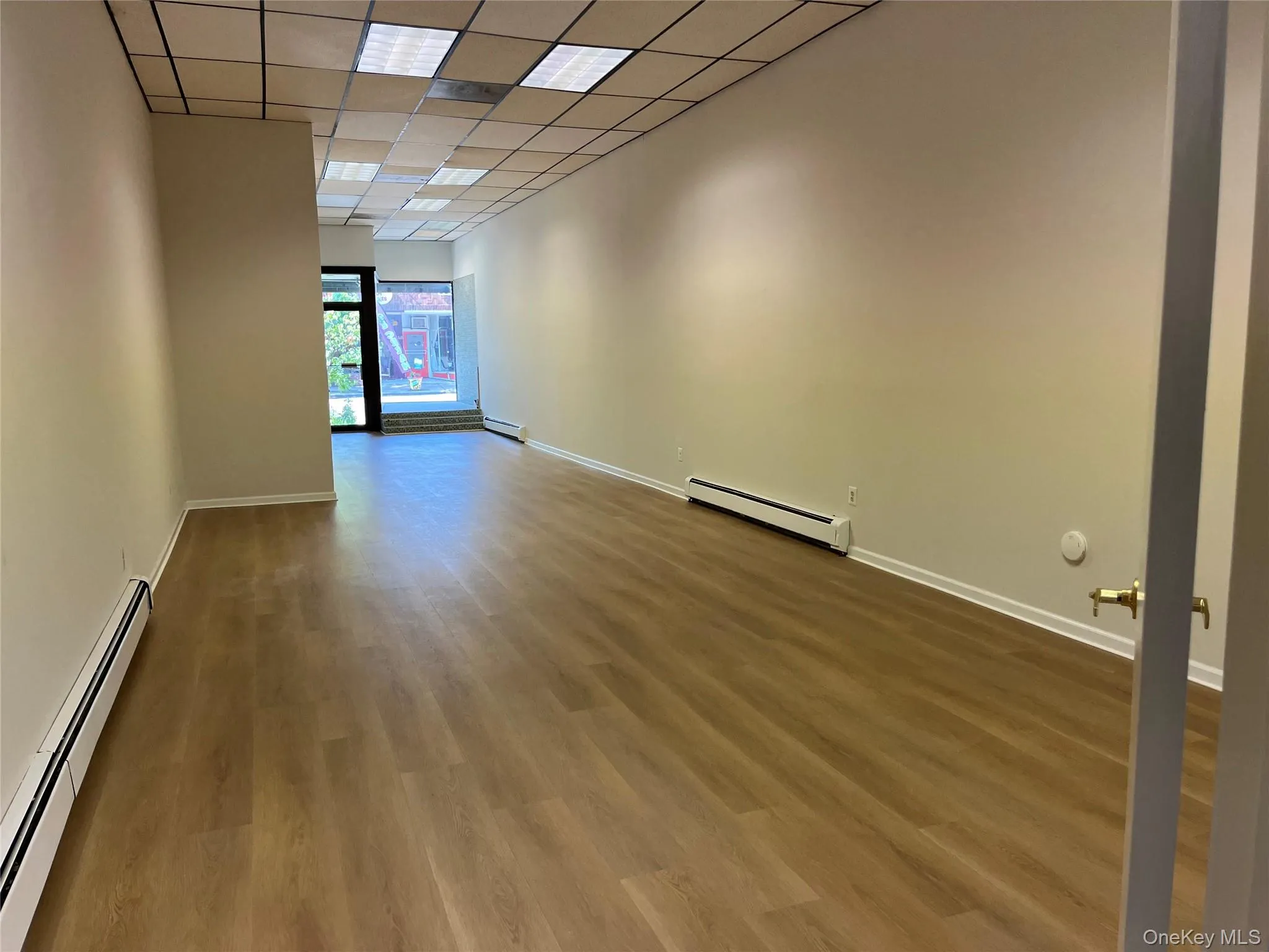 Spare room featuring a baseboard radiator, a paneled ceiling, and wood finished floors Spare room featuring a baseboard radiator, a paneled ceiling, and wood finished floors