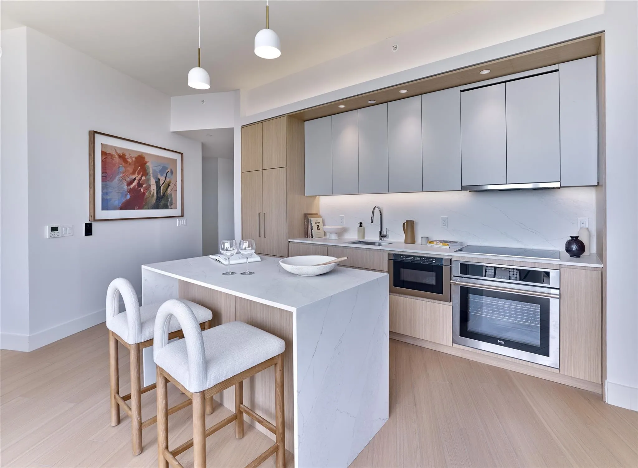 Kitchen featuring modern cabinets, stainless steel oven, a kitchen breakfast bar, and light wood finished floors Kitchen featuring modern cabinets, stainless steel oven, a kitchen breakfast bar, and light wood finished floors
