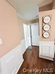 Corridor featuring wainscoting, crown molding, a decorative wall, and dark wood-style floors Corridor featuring wainscoting, crown molding, a decorative wall, and dark wood-style floors