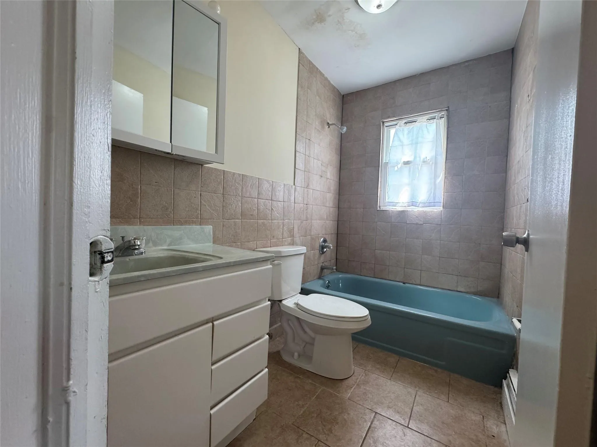 Bathroom featuring tile walls, vanity, shower / tub combination, and tile patterned floors Bathroom featuring tile walls, vanity, shower / tub combination, and tile patterned floors
