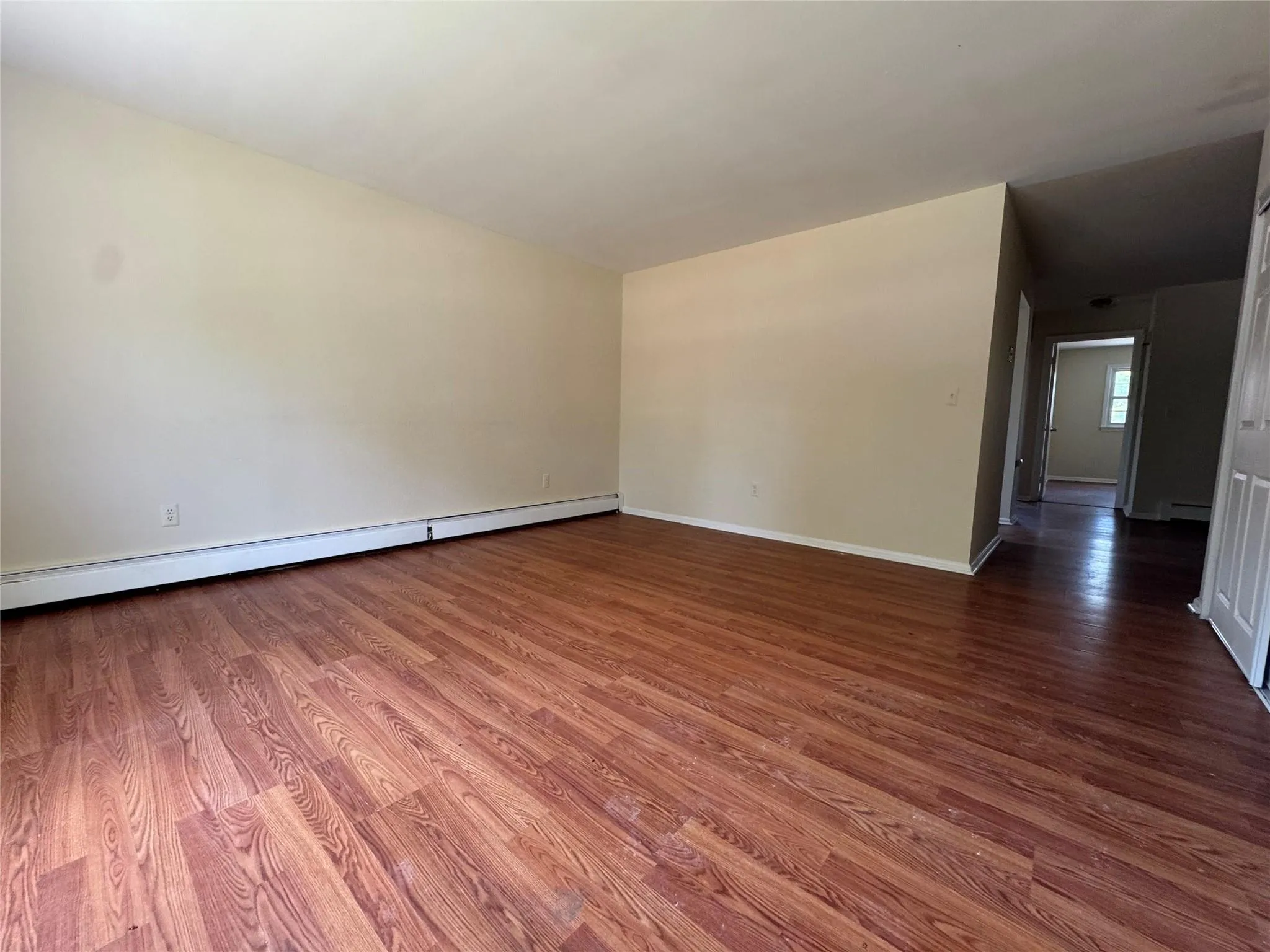 Unfurnished room with a baseboard radiator and wood finished floors Unfurnished room with a baseboard radiator and wood finished floors