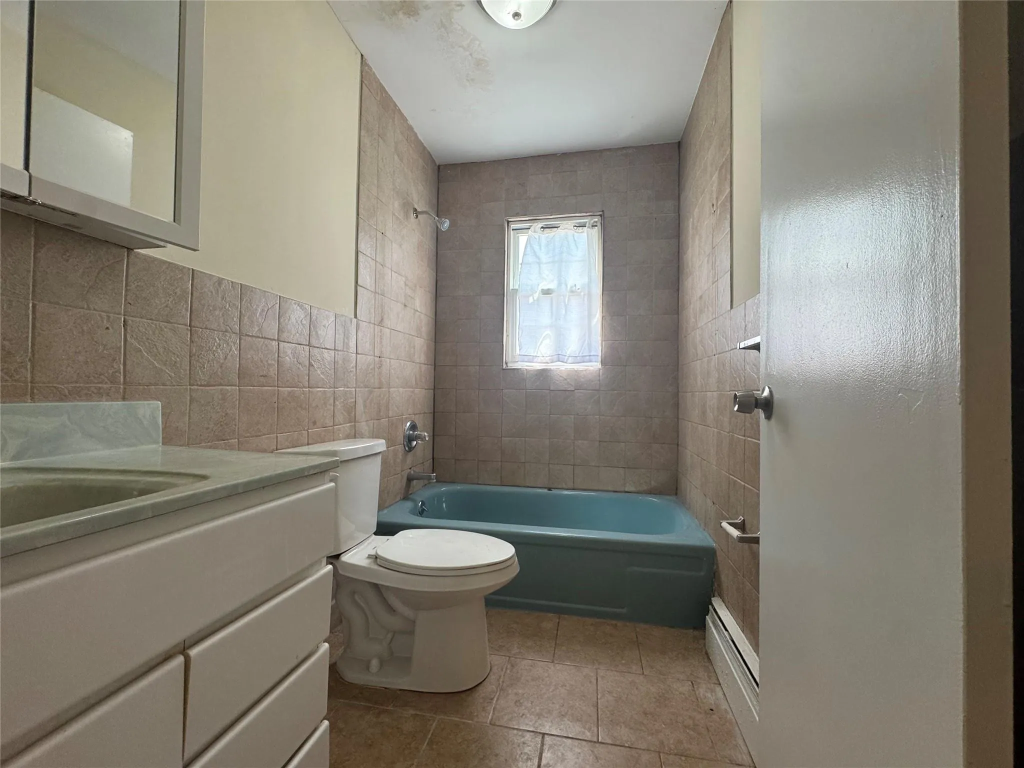 Full bathroom featuring tile walls, vanity, and shower / bath combination Full bathroom featuring tile walls, vanity, and shower / bath combination