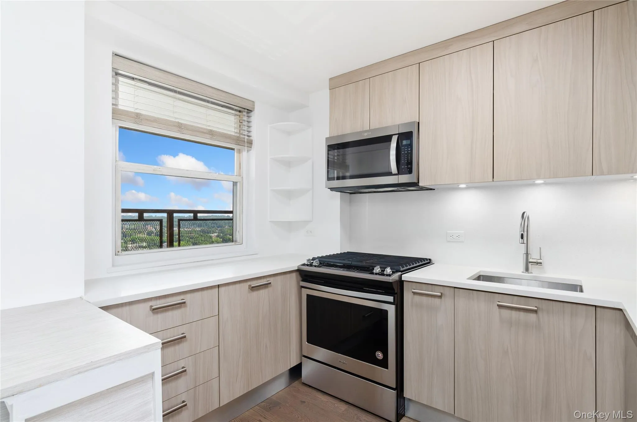 Kitchen with appliances with stainless steel finishes, modern cabinets, light brown cabinetry, and light countertops Kitchen with appliances with stainless steel finishes, modern cabinets, light brown cabinetry, and light countertops