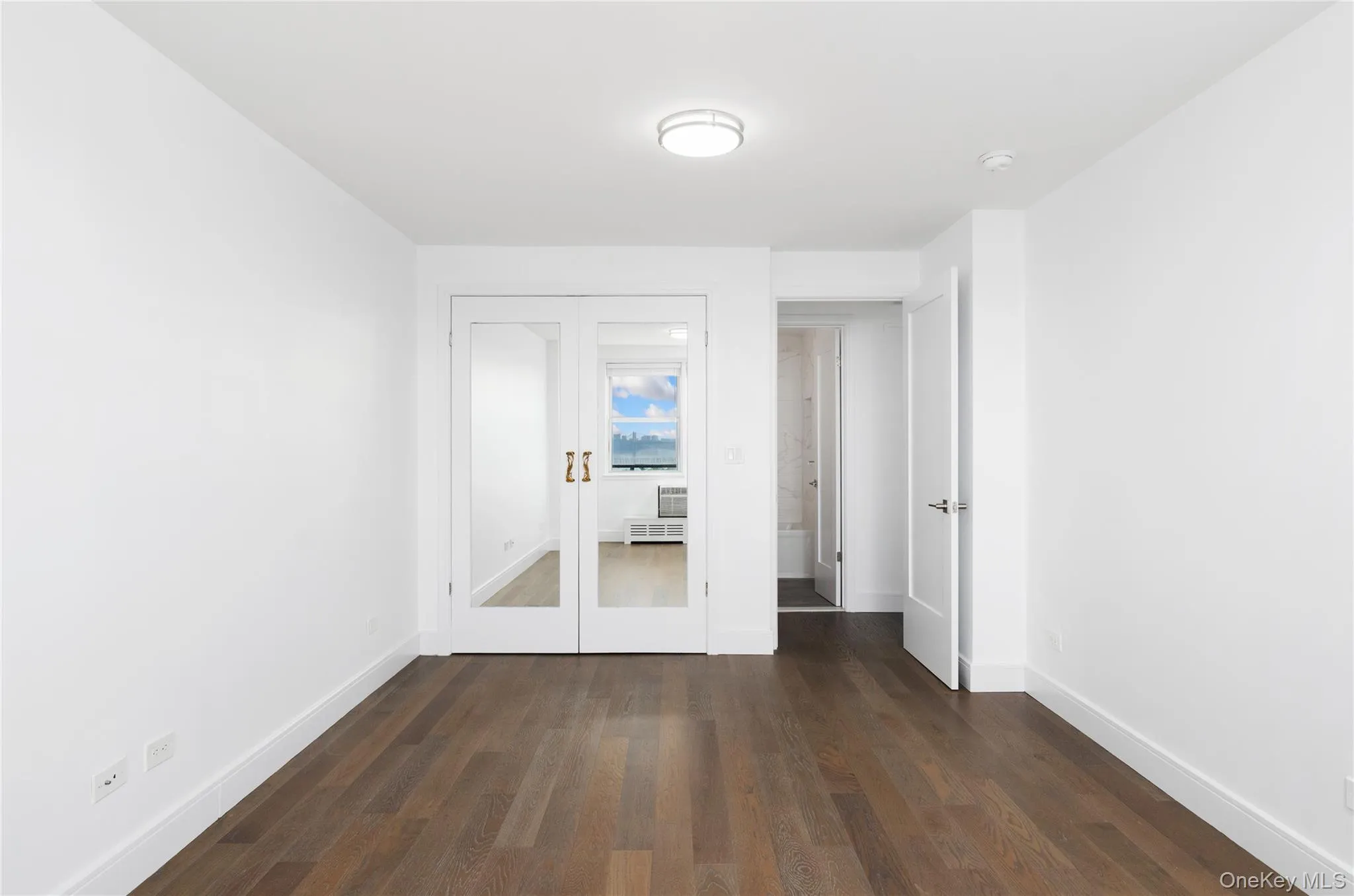 Unfurnished bedroom featuring dark wood finished floors and french doors Unfurnished bedroom featuring dark wood finished floors and french doors