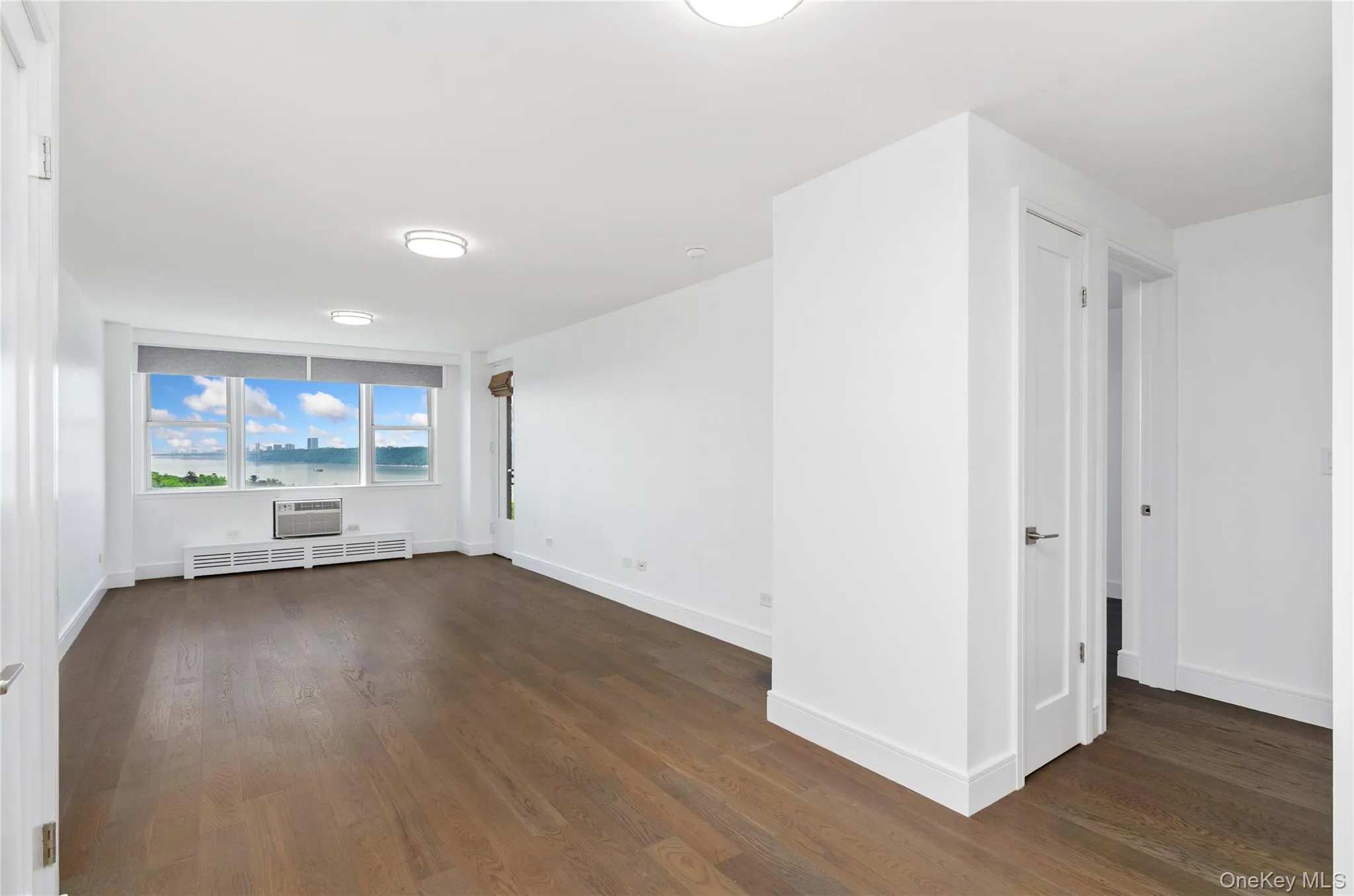 Unfurnished room with dark wood-style floors and a wall mounted air conditioner Unfurnished room with dark wood-style floors and a wall mounted air conditioner