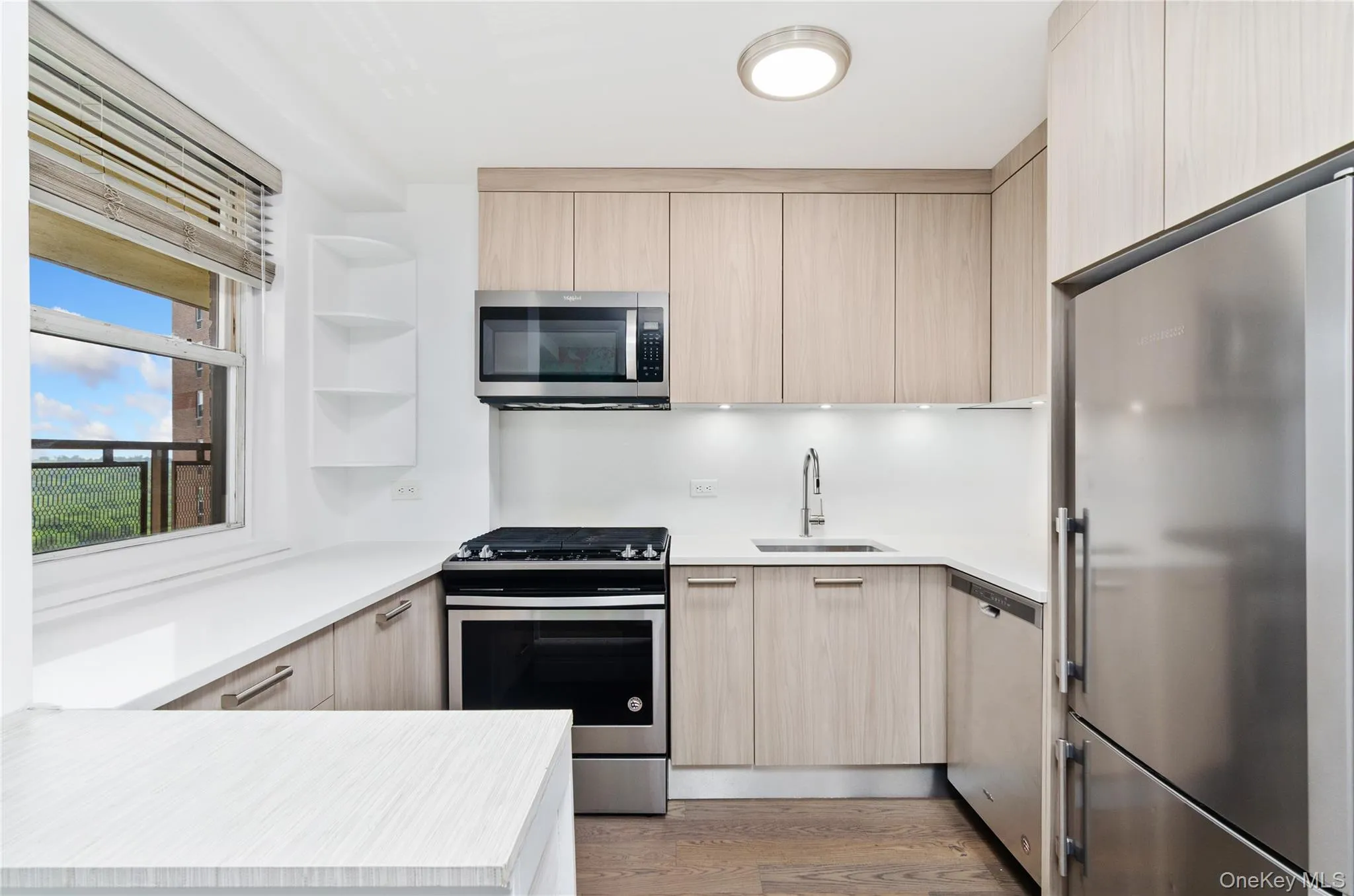 Kitchen with stainless steel appliances, light brown cabinetry, and modern cabinets Kitchen with stainless steel appliances, light brown cabinetry, and modern cabinets