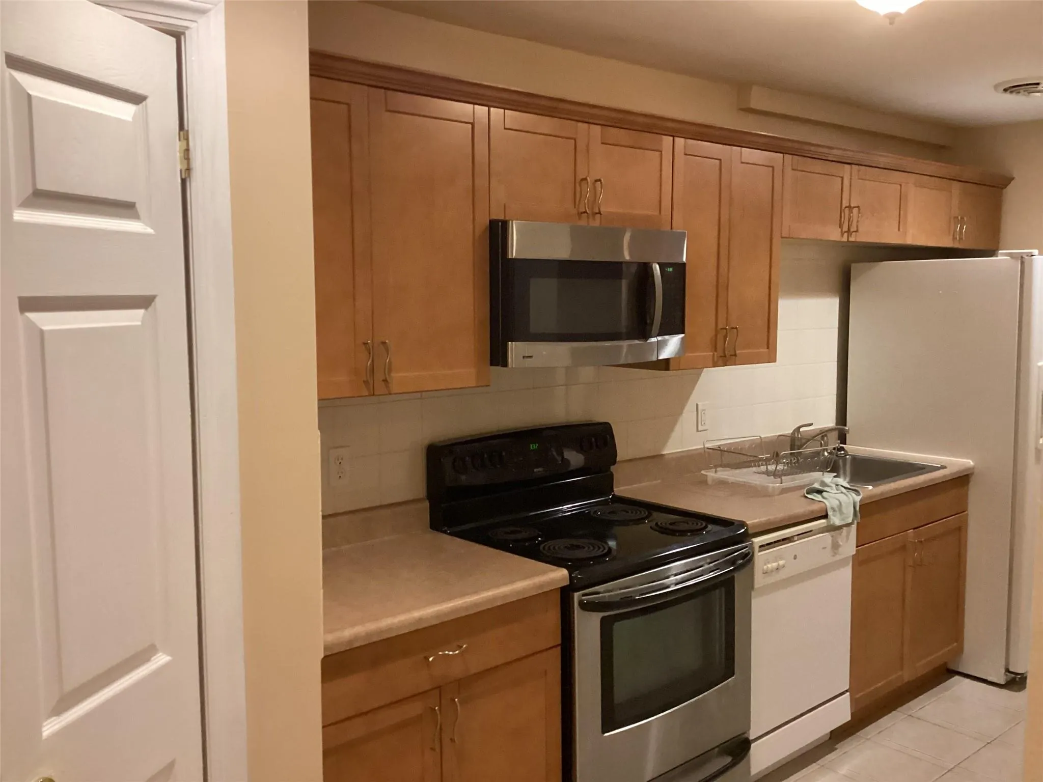 Kitchen featuring stainless steel appliances, light countertops, backsplash, and light tile patterned flooring Kitchen featuring stainless steel appliances, light countertops, backsplash, and light tile patterned flooring