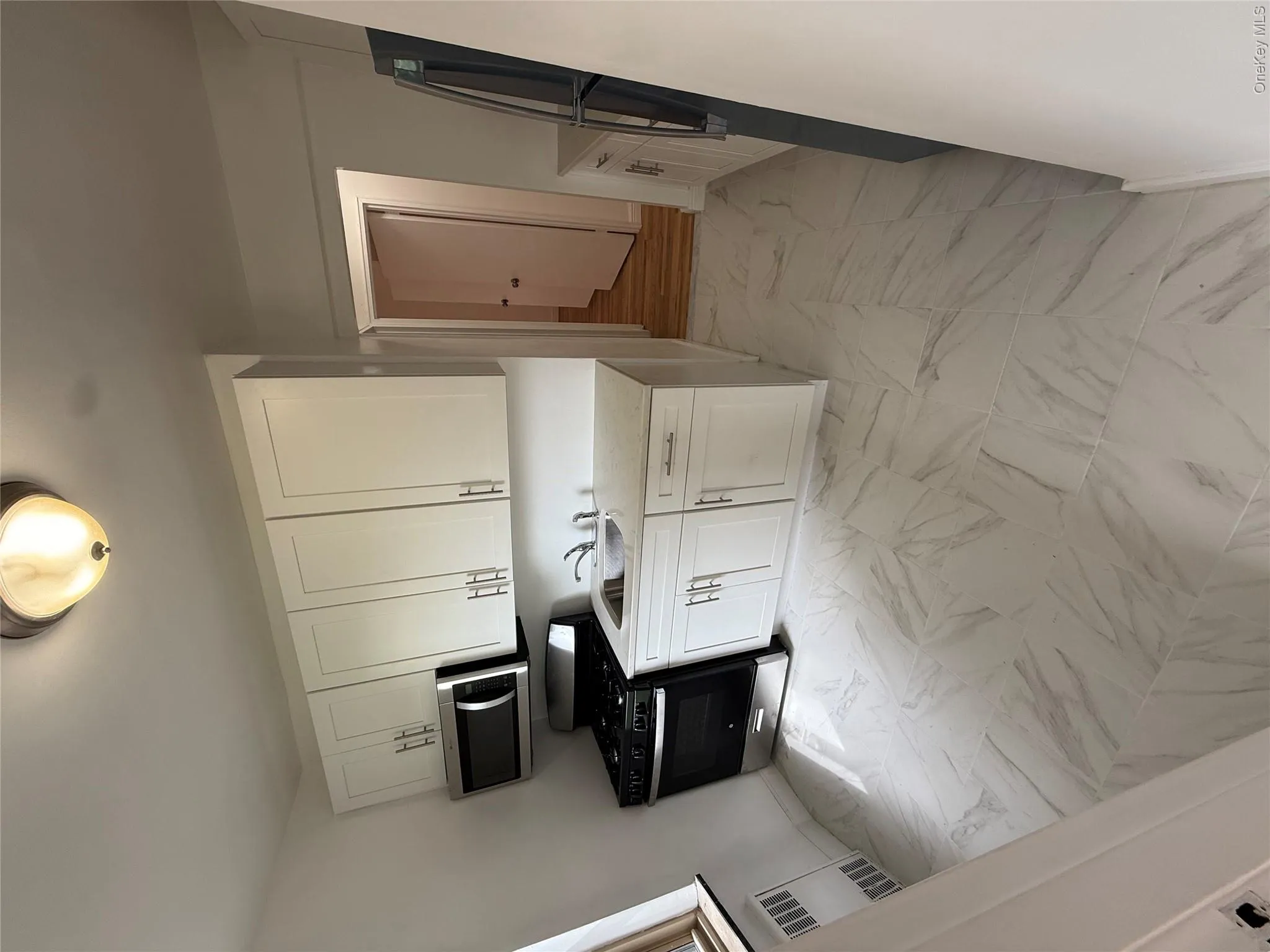 Kitchen featuring stove, light marble finish floors, white cabinetry, and light countertops Kitchen featuring stove, light marble finish floors, white cabinetry, and light countertops