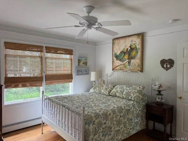 Bedroom with a baseboard heating unit, wood finished floors, and a ceiling fan Bedroom with a baseboard heating unit, wood finished floors, and a ceiling fan