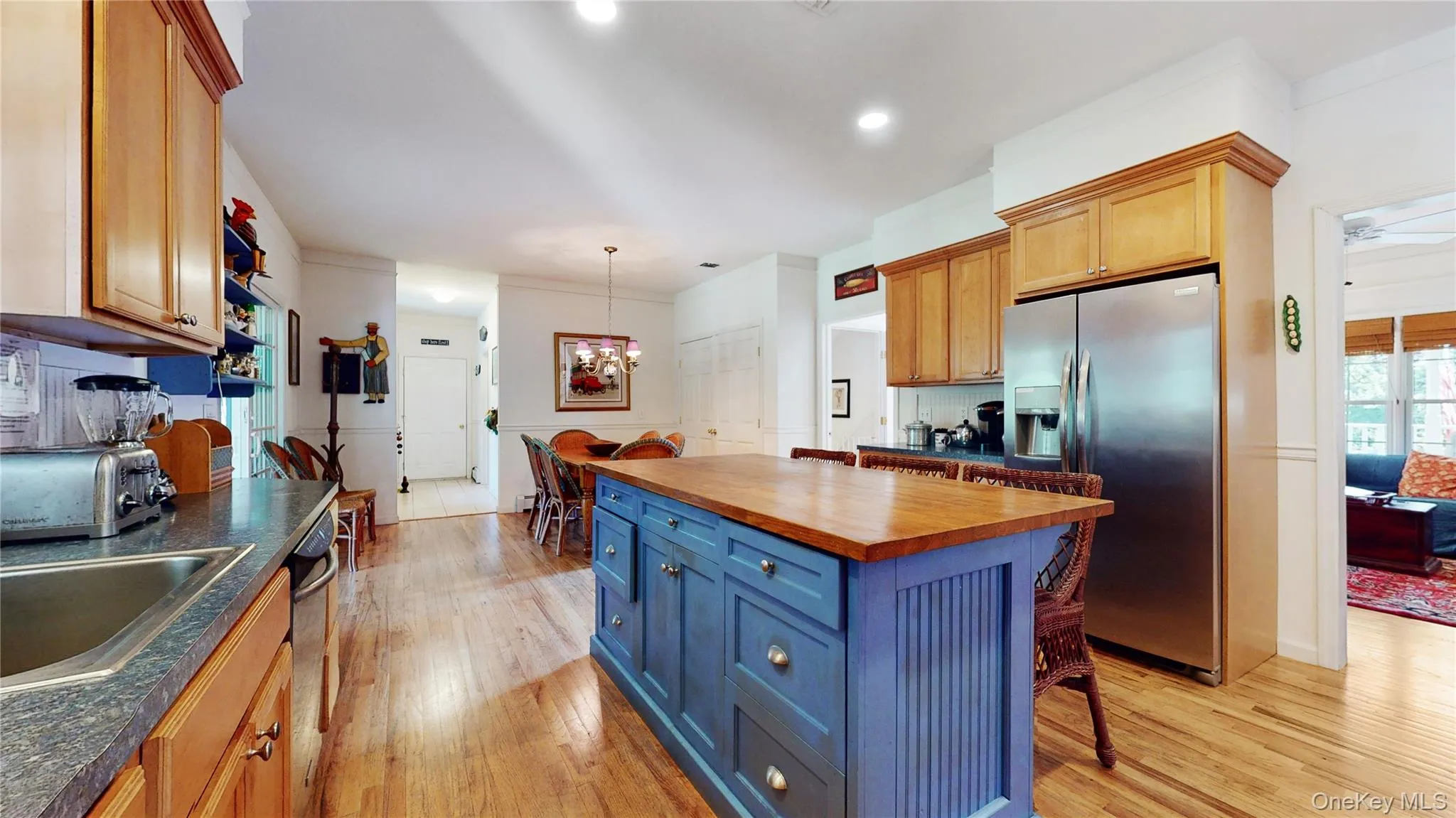 Kitchen with appliances with stainless steel finishes, butcher block counters, light wood finished floors, a kitchen breakfast bar, and a chandelier Kitchen with appliances with stainless steel finishes, butcher block counters, light wood finished floors, a kitchen breakfast bar, and a chandelier