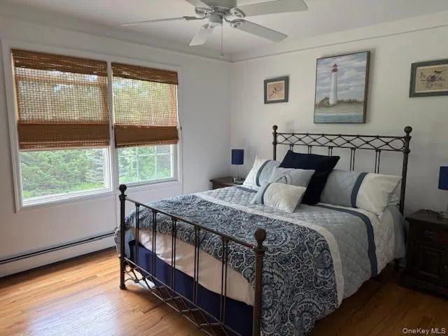 Bedroom with wood finished floors, a baseboard radiator, and ceiling fan Bedroom with wood finished floors, a baseboard radiator, and ceiling fan