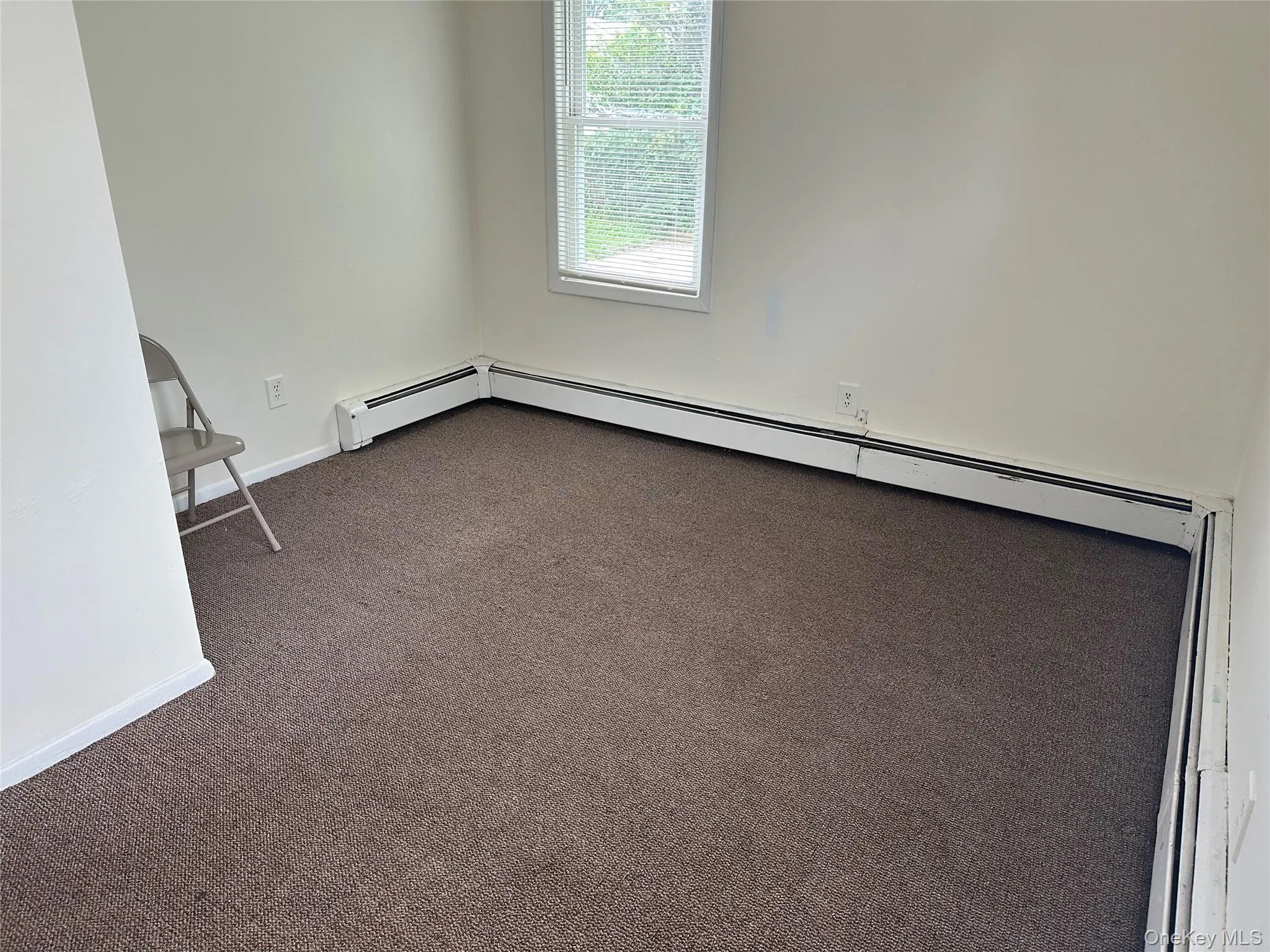 Unfurnished room featuring dark colored carpet and baseboards Unfurnished room featuring dark colored carpet and baseboards
