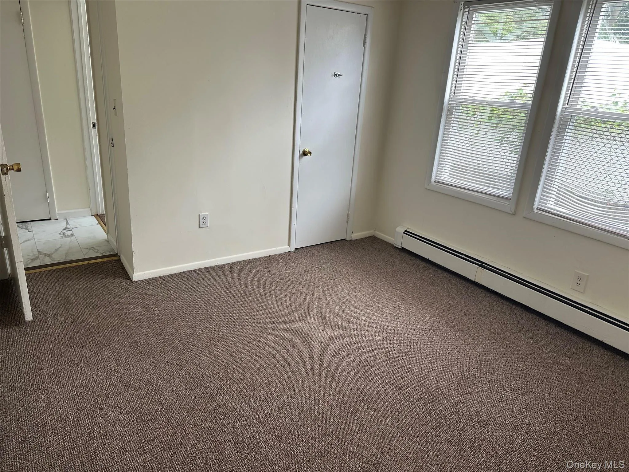 Unfurnished bedroom with baseboard heating and carpet floors Unfurnished bedroom with baseboard heating and carpet floors