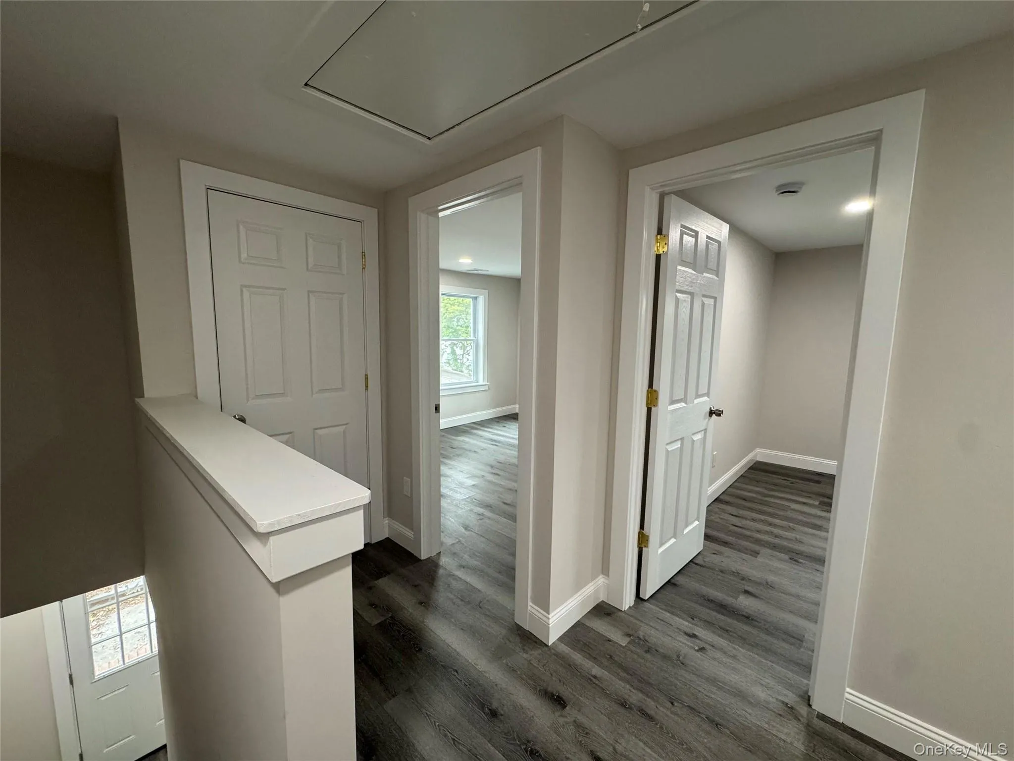 Hallway featuring dark wood-style flooring and attic access Hallway featuring dark wood-style flooring and attic access