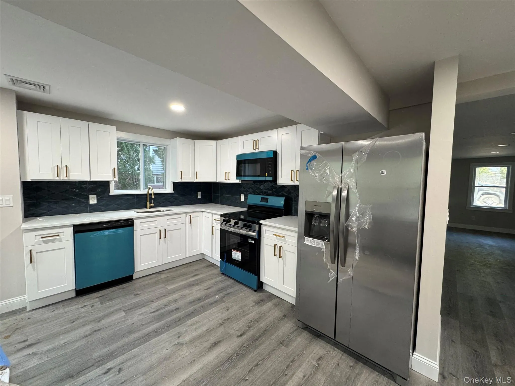Kitchen with stainless steel appliances, white cabinetry, backsplash, and light wood-type flooring Kitchen with stainless steel appliances, white cabinetry, backsplash, and light wood-type flooring