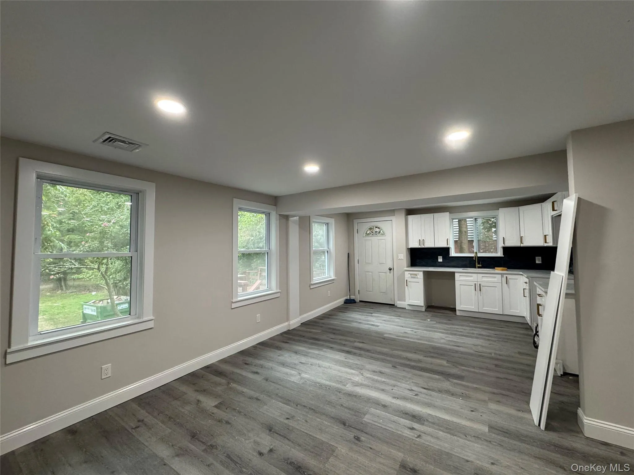 Kitchen with white cabinetry, dark wood-type flooring, recessed lighting, decorative backsplash, and dishwasher Kitchen with white cabinetry, dark wood-type flooring, recessed lighting, decorative backsplash, and dishwasher