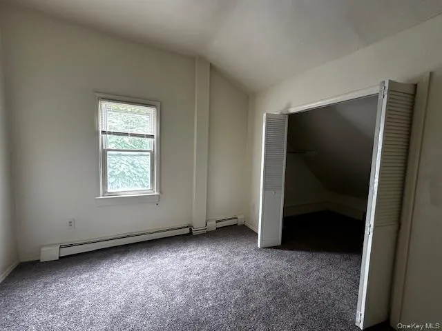 PrimaryUnfurnished bedroom with lofted ceiling, carpet flooring, and a baseboard radiator PrimaryUnfurnished bedroom with lofted ceiling, carpet flooring, and a baseboard radiator