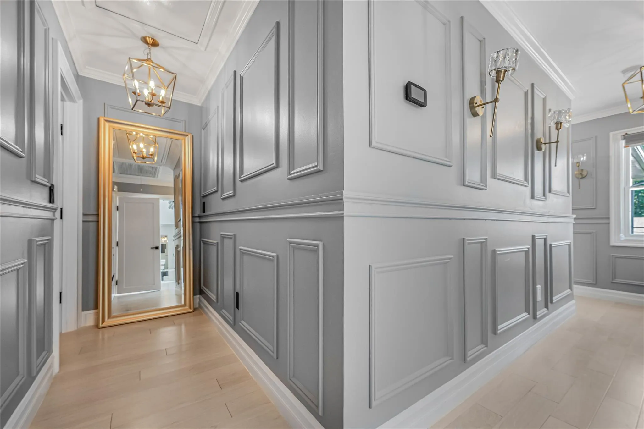 Hallway with a decorative wall, crown molding, and a chandelier Hallway with a decorative wall, crown molding, and a chandelier