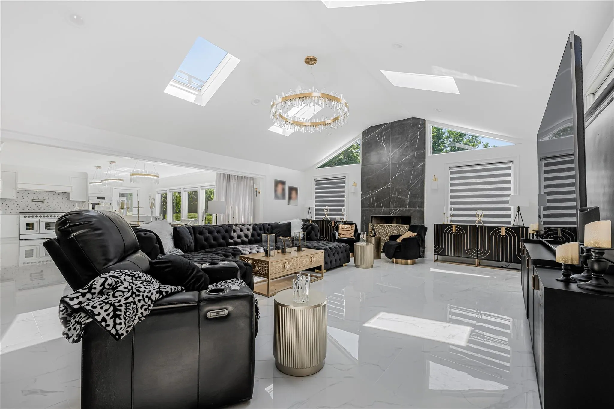 Living room with a skylight, vaulted ceiling, marble tiled flooring, and a premium fireplace Living room with a skylight, vaulted ceiling, marble tiled flooring, and a premium fireplace