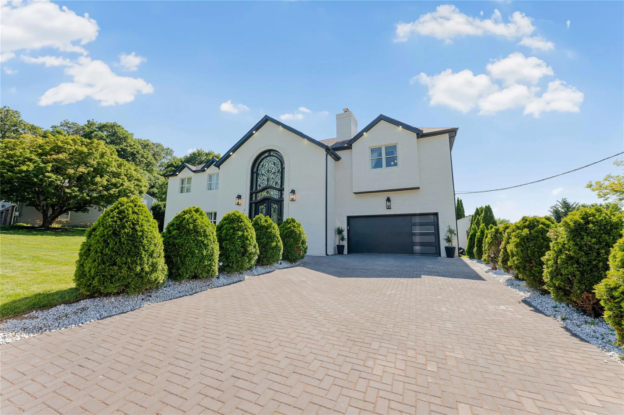 View of front of home featuring decorative driveway, an attached garage, a chimney, stucco siding, and a front yard View of front of home featuring decorative driveway, an attached garage, a chimney, stucco siding, and a front yard