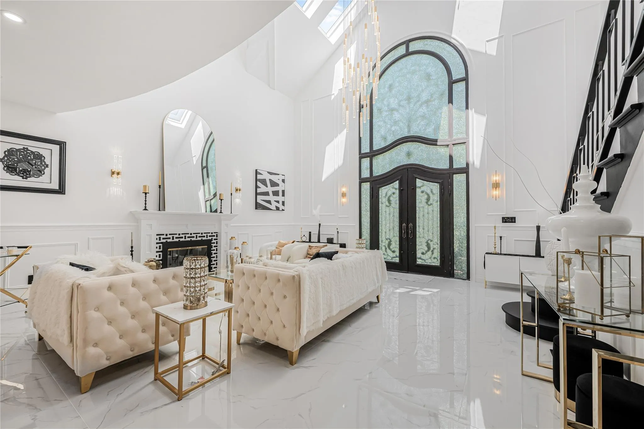 Living room featuring a decorative wall, light marble finish floors, a high ceiling, french doors, and a wainscoted wall Living room featuring a decorative wall, light marble finish floors, a high ceiling, french doors, and a wainscoted wall