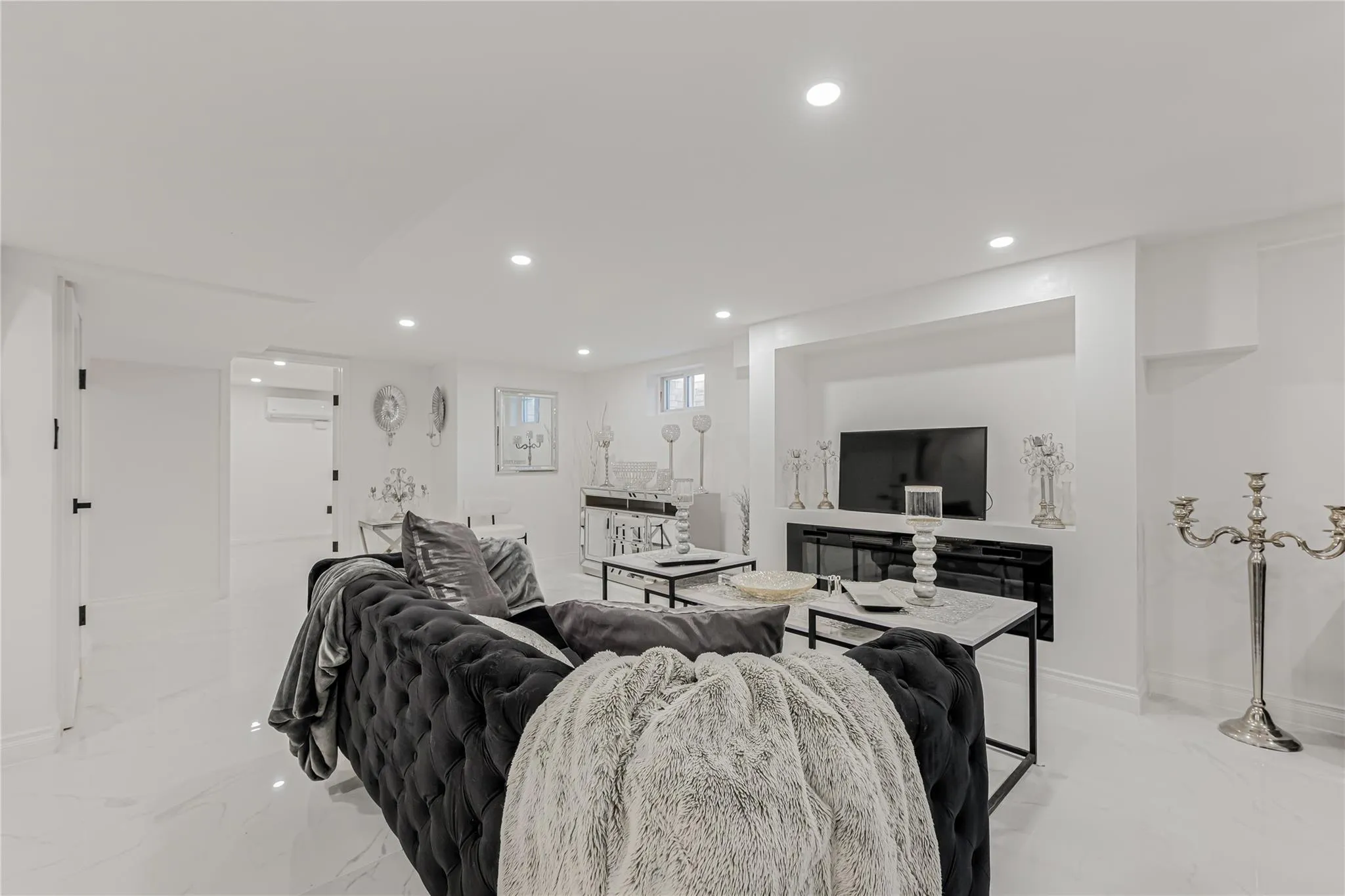 Living area featuring light marble finish floors, recessed lighting, and an AC wall unit Living area featuring light marble finish floors, recessed lighting, and an AC wall unit