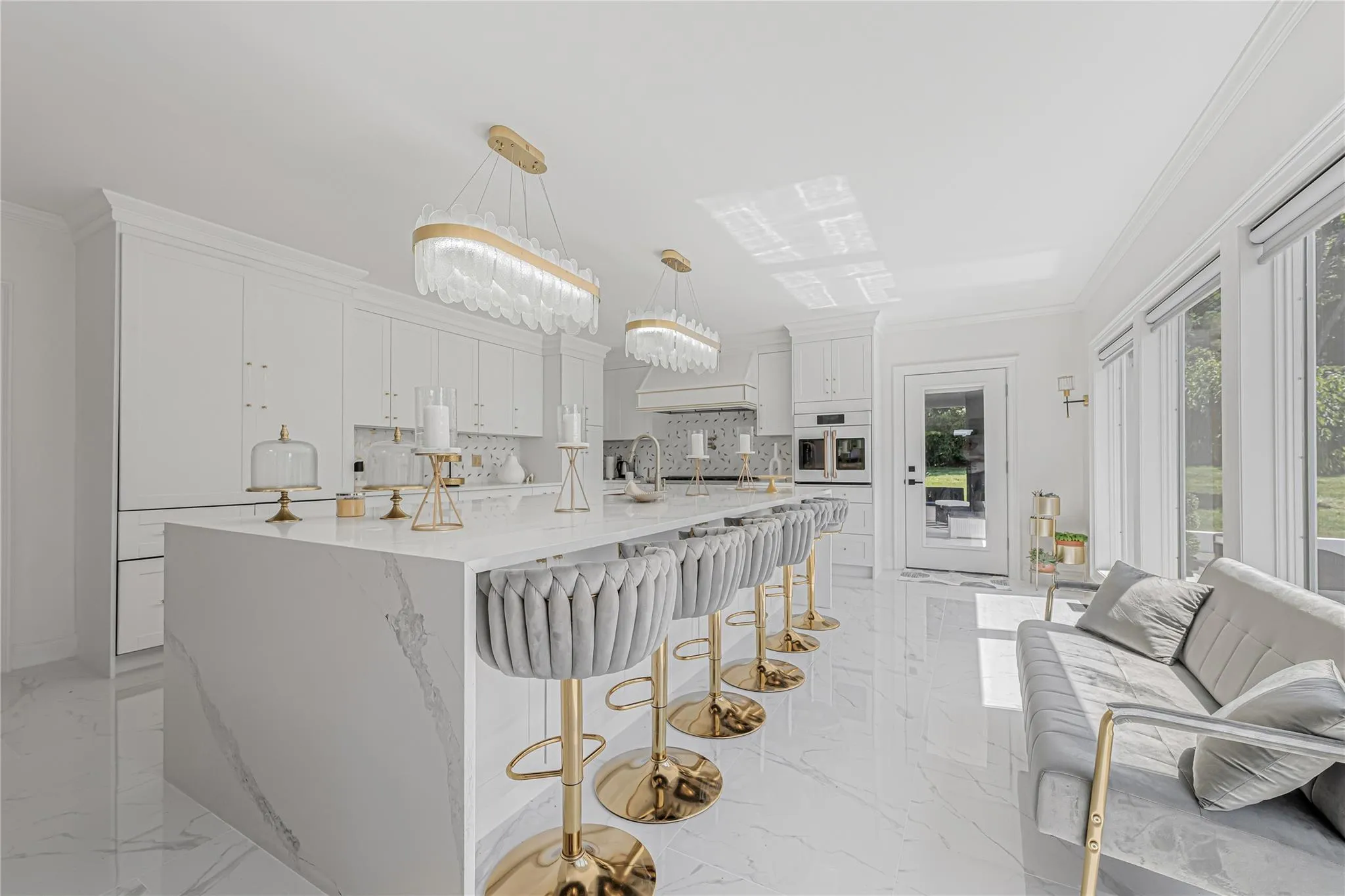 Kitchen featuring light marble finish floors, white oven, tasteful backsplash, white cabinetry, and a kitchen breakfast bar Kitchen featuring light marble finish floors, white oven, tasteful backsplash, white cabinetry, and a kitchen breakfast bar