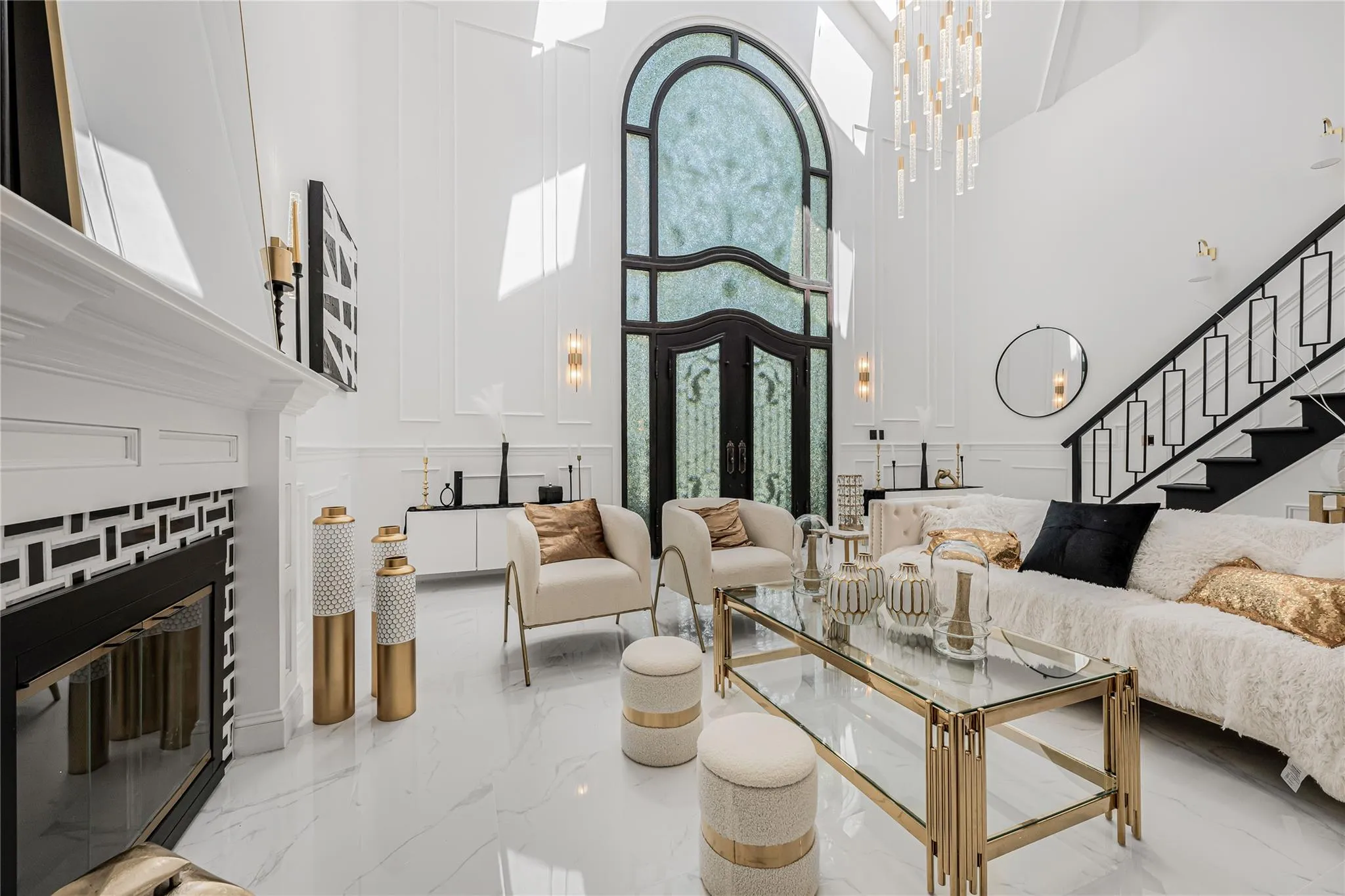 Living area with a towering ceiling, a decorative wall, stairs, marble tiled floors, and a fireplace Living area with a towering ceiling, a decorative wall, stairs, marble tiled floors, and a fireplace