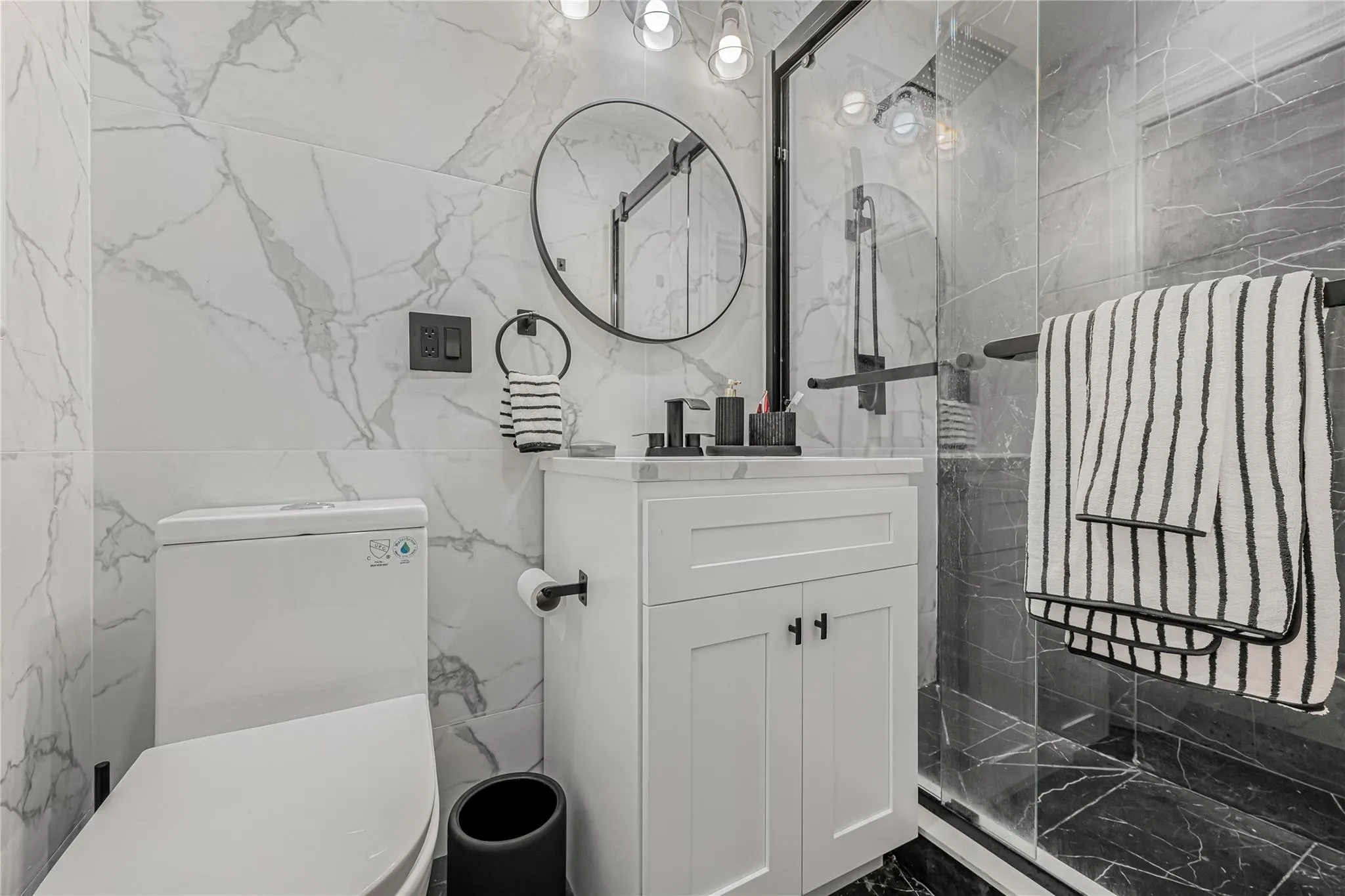 Full bath featuring tile walls, vanity, a marble finish shower, and marble finish floors Full bath featuring tile walls, vanity, a marble finish shower, and marble finish floors