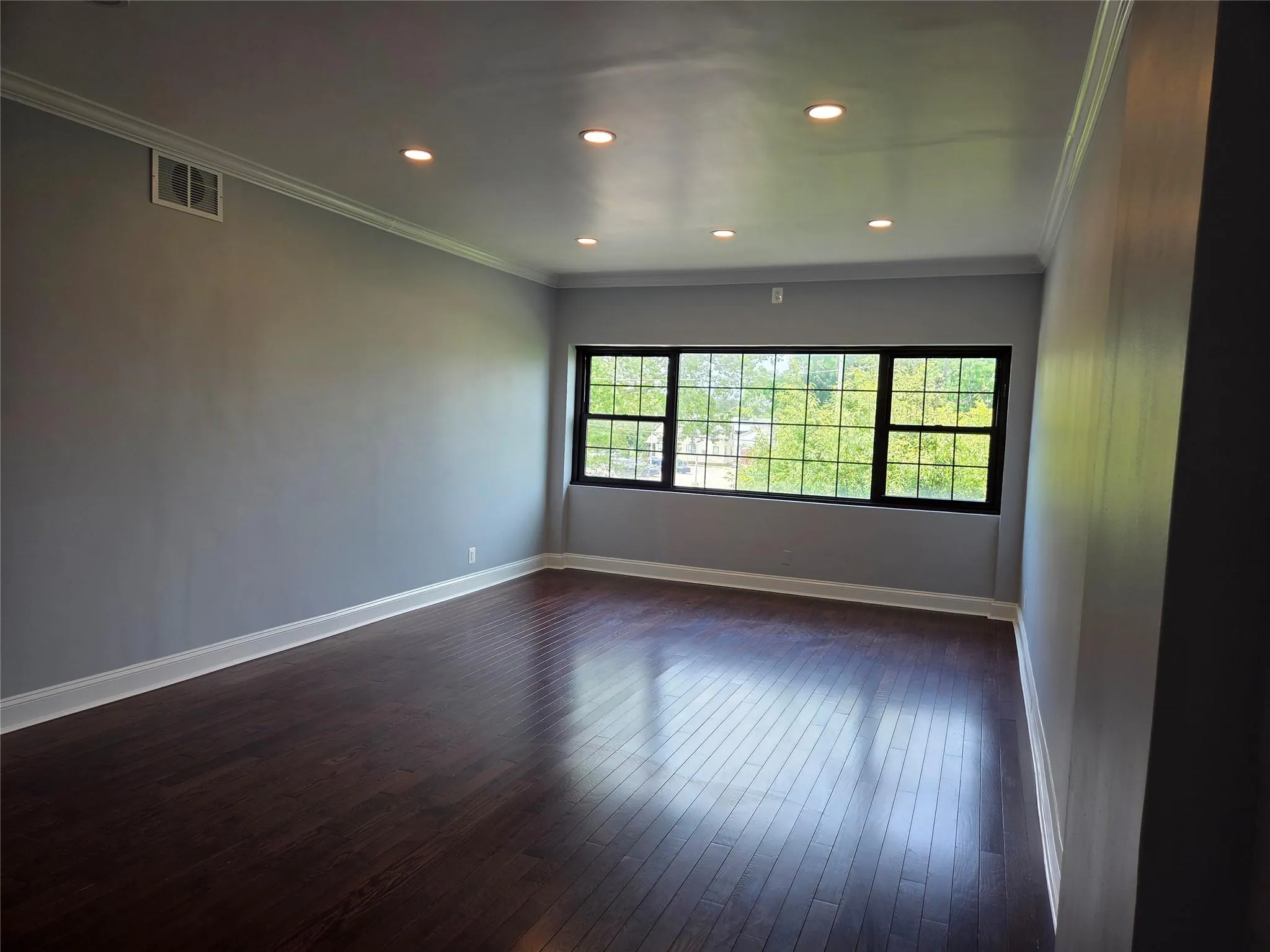 Spare room featuring dark wood-style flooring, ornamental molding, and recessed lighting Spare room featuring dark wood-style flooring, ornamental molding, and recessed lighting