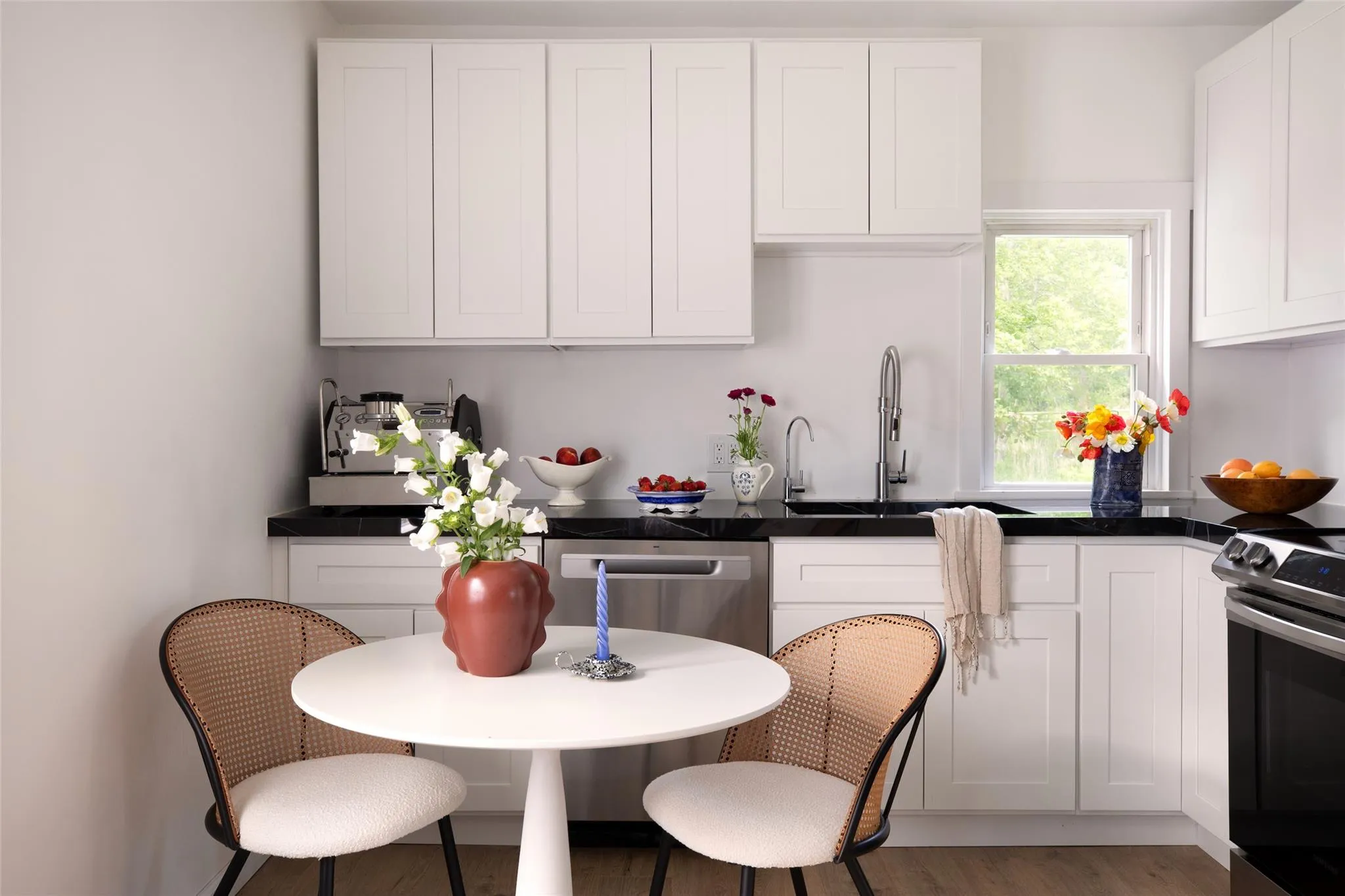 Kitchen featuring appliances with stainless steel finishes, white cabinets, dark countertops, and wood finished floors Kitchen featuring appliances with stainless steel finishes, white cabinets, dark countertops, and wood finished floors