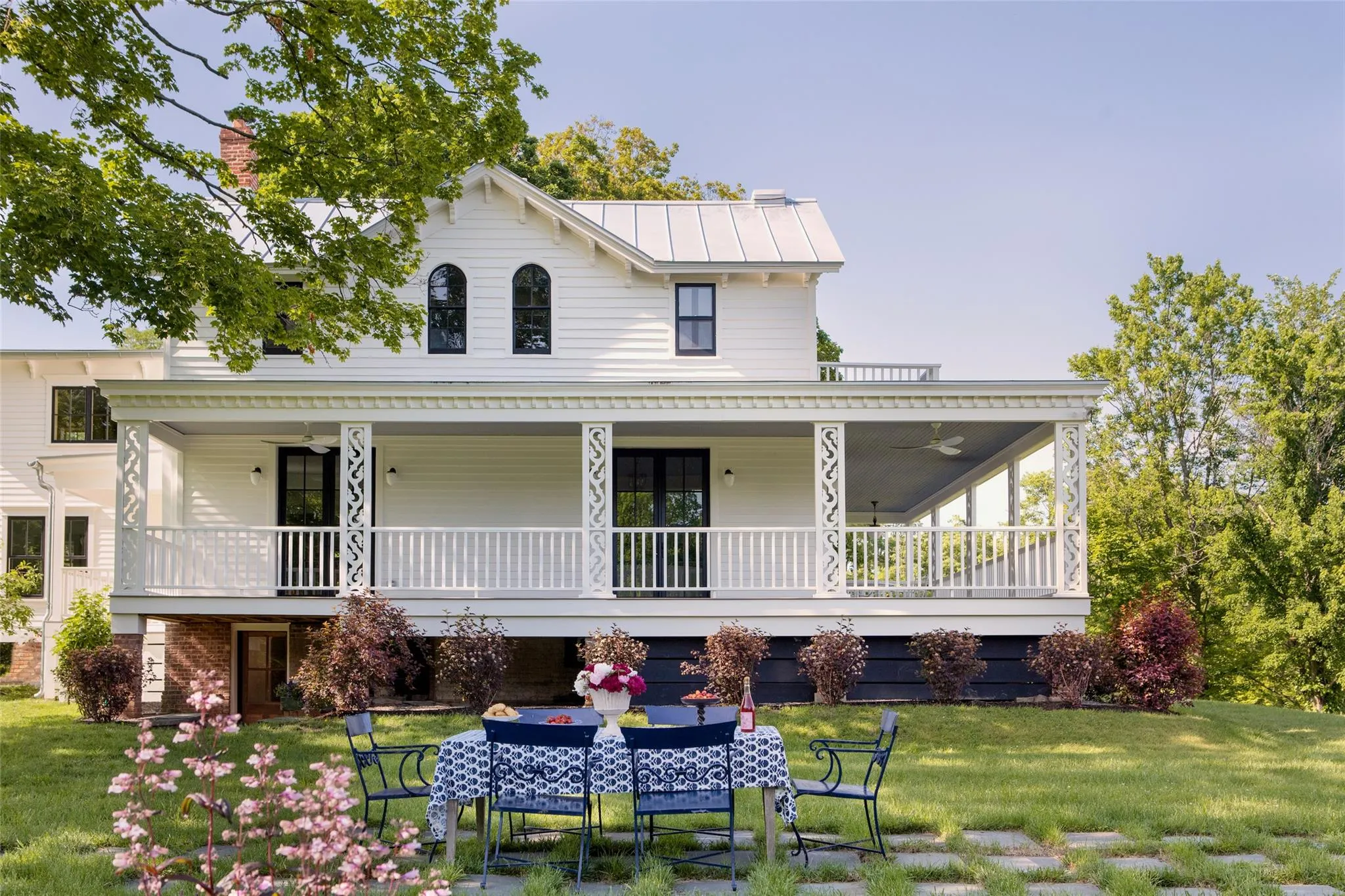 Farmhouse inspired home featuring a front yard, outdoor dining space, and a porch Farmhouse inspired home featuring a front yard, outdoor dining space, and a porch