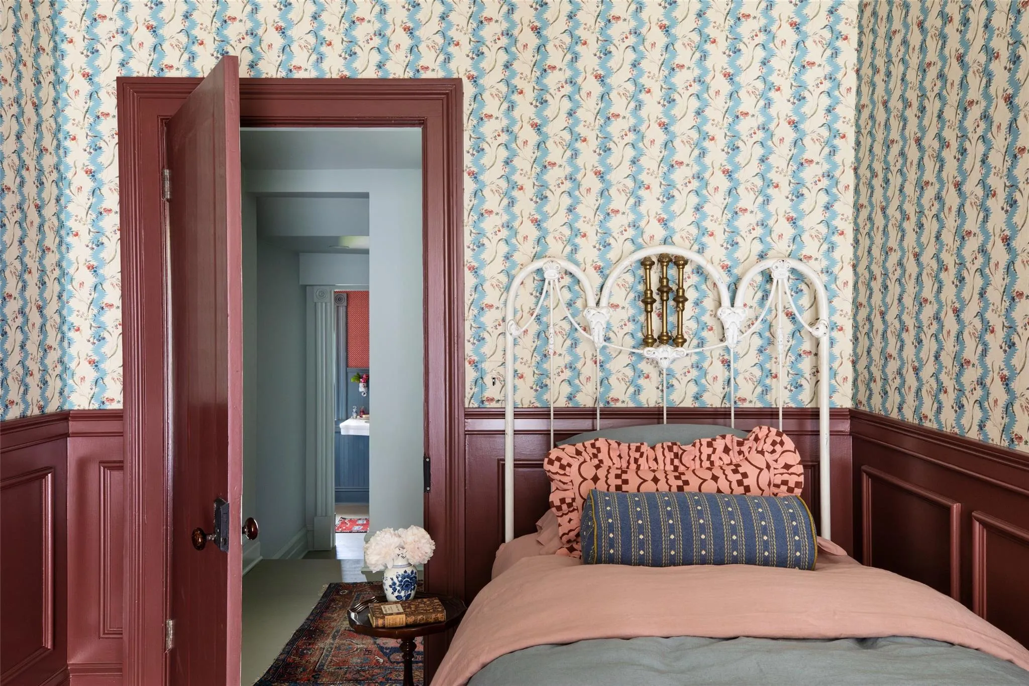 Bedroom featuring wainscoting, wallpapered walls, and a decorative wall Bedroom featuring wainscoting, wallpapered walls, and a decorative wall