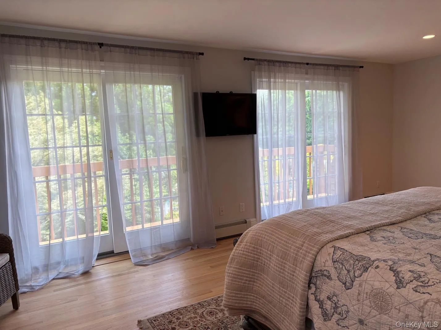 Bedroom with wood finished floors, a baseboard heating unit, access to exterior, and recessed lighting Bedroom with wood finished floors, a baseboard heating unit, access to exterior, and recessed lighting