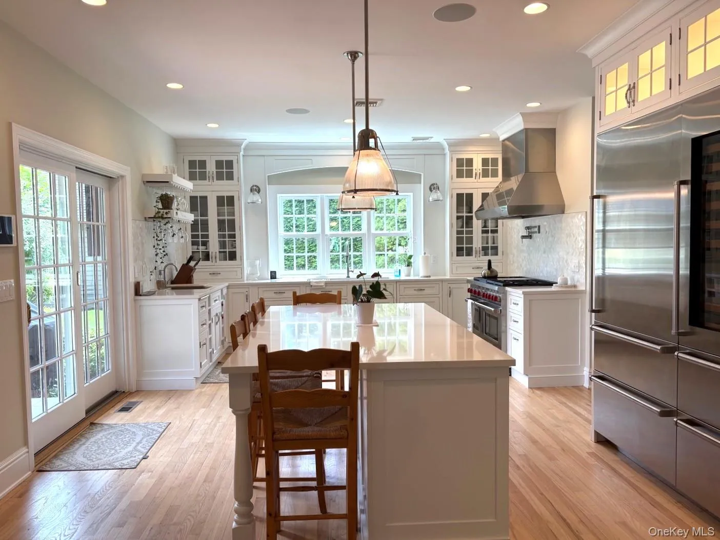 Kitchen with premium appliances, wall chimney exhaust hood, decorative backsplash, light countertops, and recessed lighting Kitchen with premium appliances, wall chimney exhaust hood, decorative backsplash, light countertops, and recessed lighting