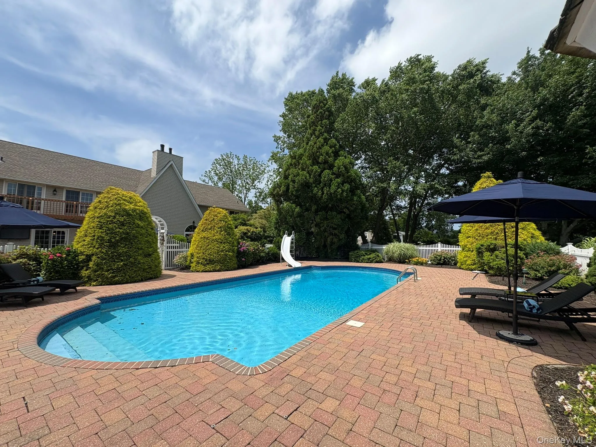 View of pool with a water slide and a patio View of pool with a water slide and a patio