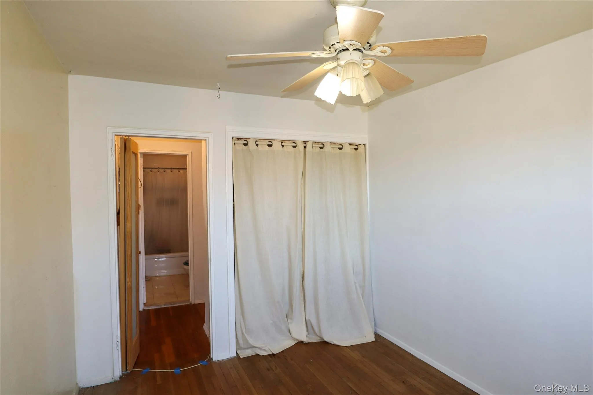 Unfurnished bedroom featuring dark wood-style floors and a ceiling fan Unfurnished bedroom featuring dark wood-style floors and a ceiling fan