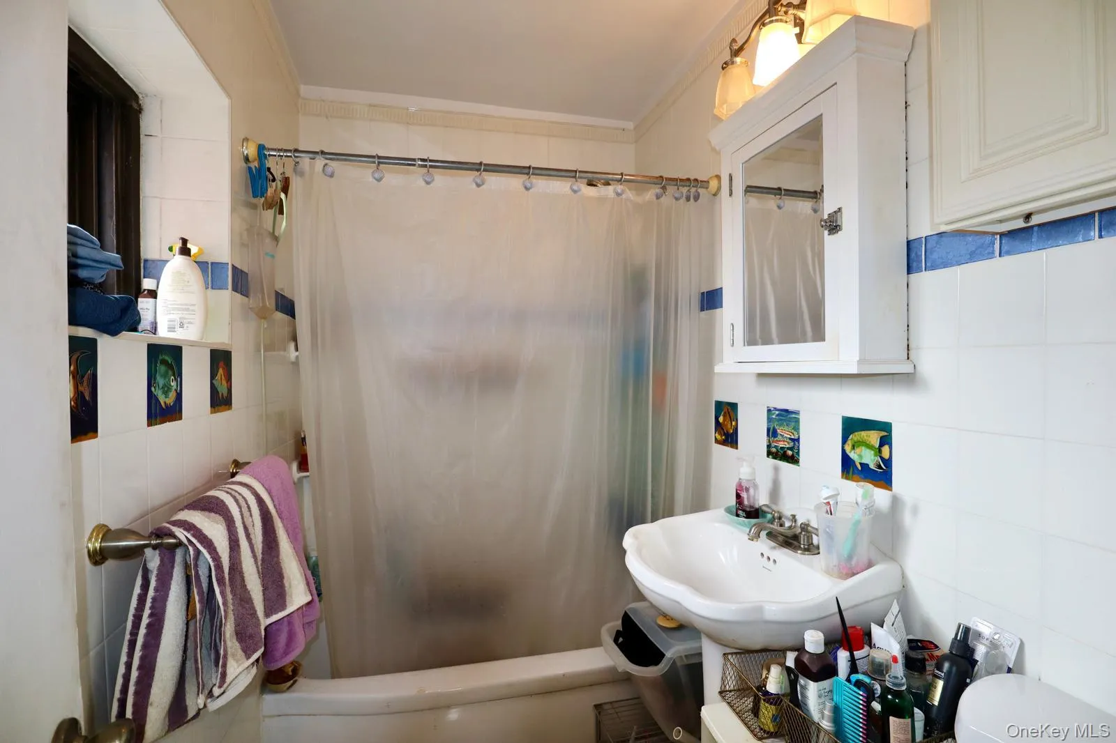 Bathroom featuring tile walls, shower / bath combination with curtain, and ornamental molding Bathroom featuring tile walls, shower / bath combination with curtain, and ornamental molding