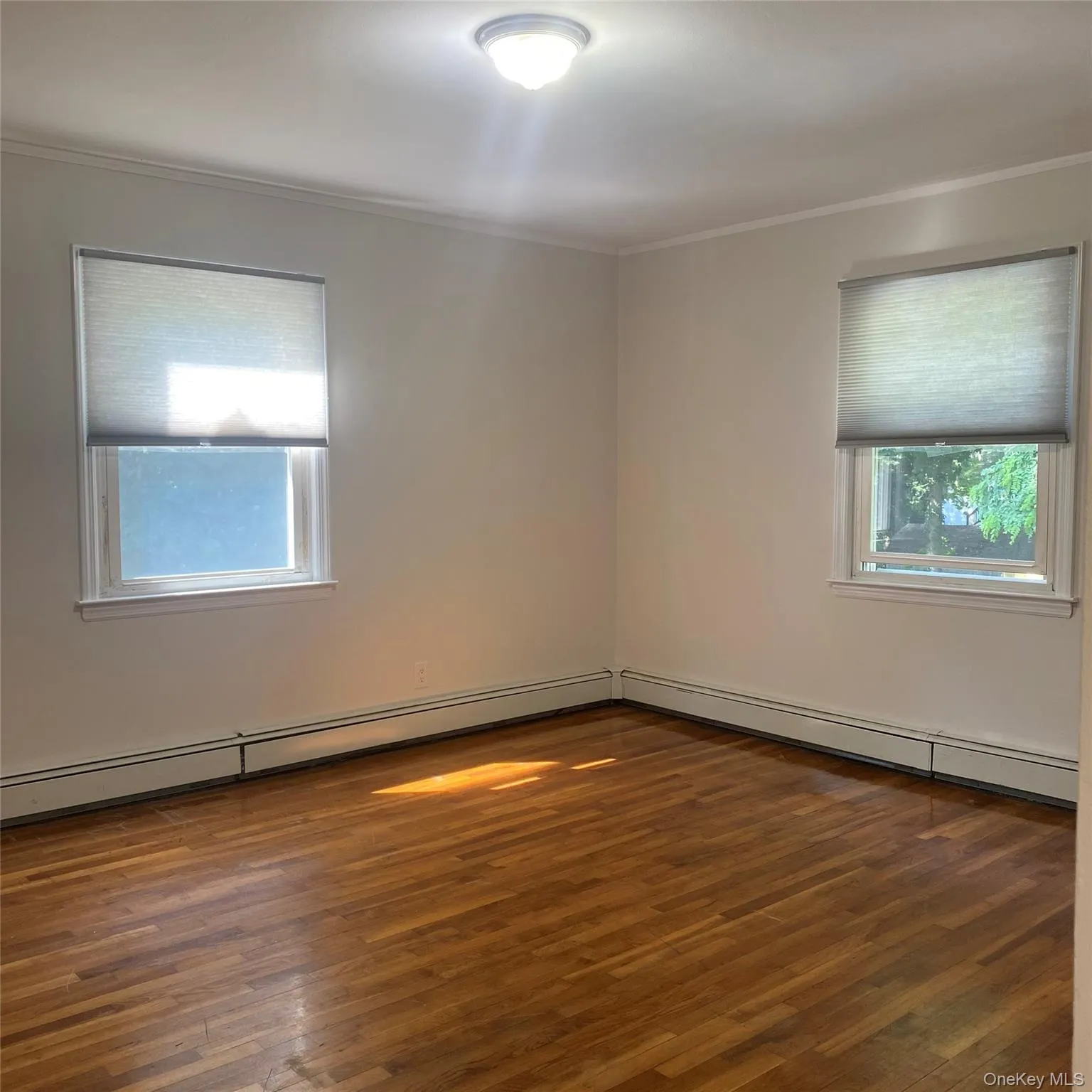 Queen size Bedroom with crown molding, plenty of natural light, wood finished floors, and baseboard heating Queen size Bedroom with crown molding, plenty of natural light, wood finished floors, and baseboard heating