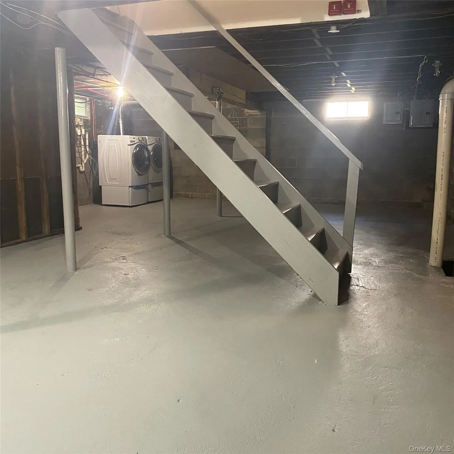 Below grade area with washing machine and clothes dryer and stairway Below grade area with washing machine and clothes dryer and stairway