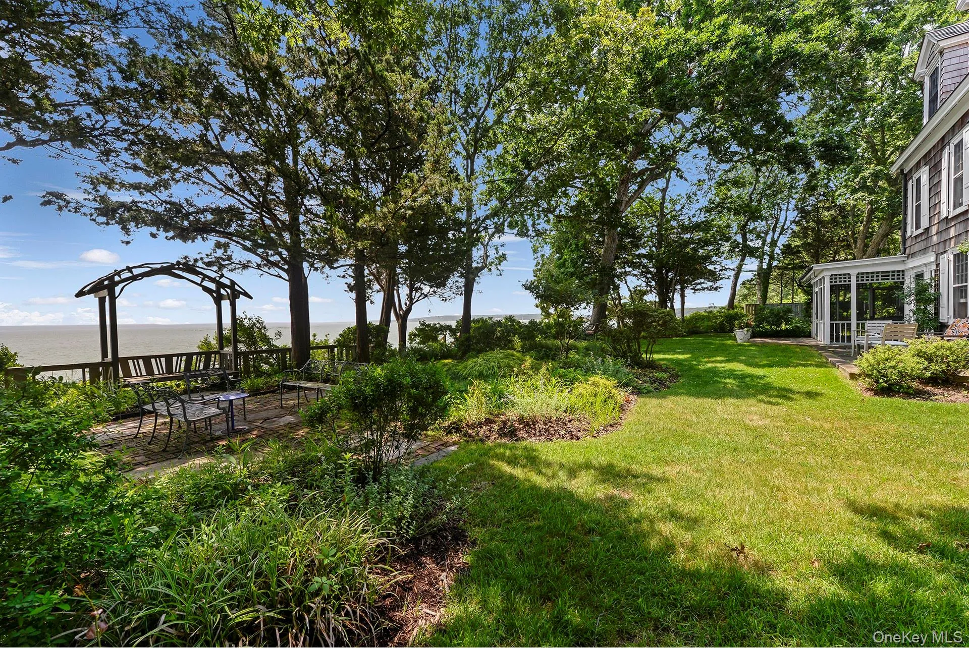 View of grassy yard featuring a water view and a patio View of grassy yard featuring a water view and a patio