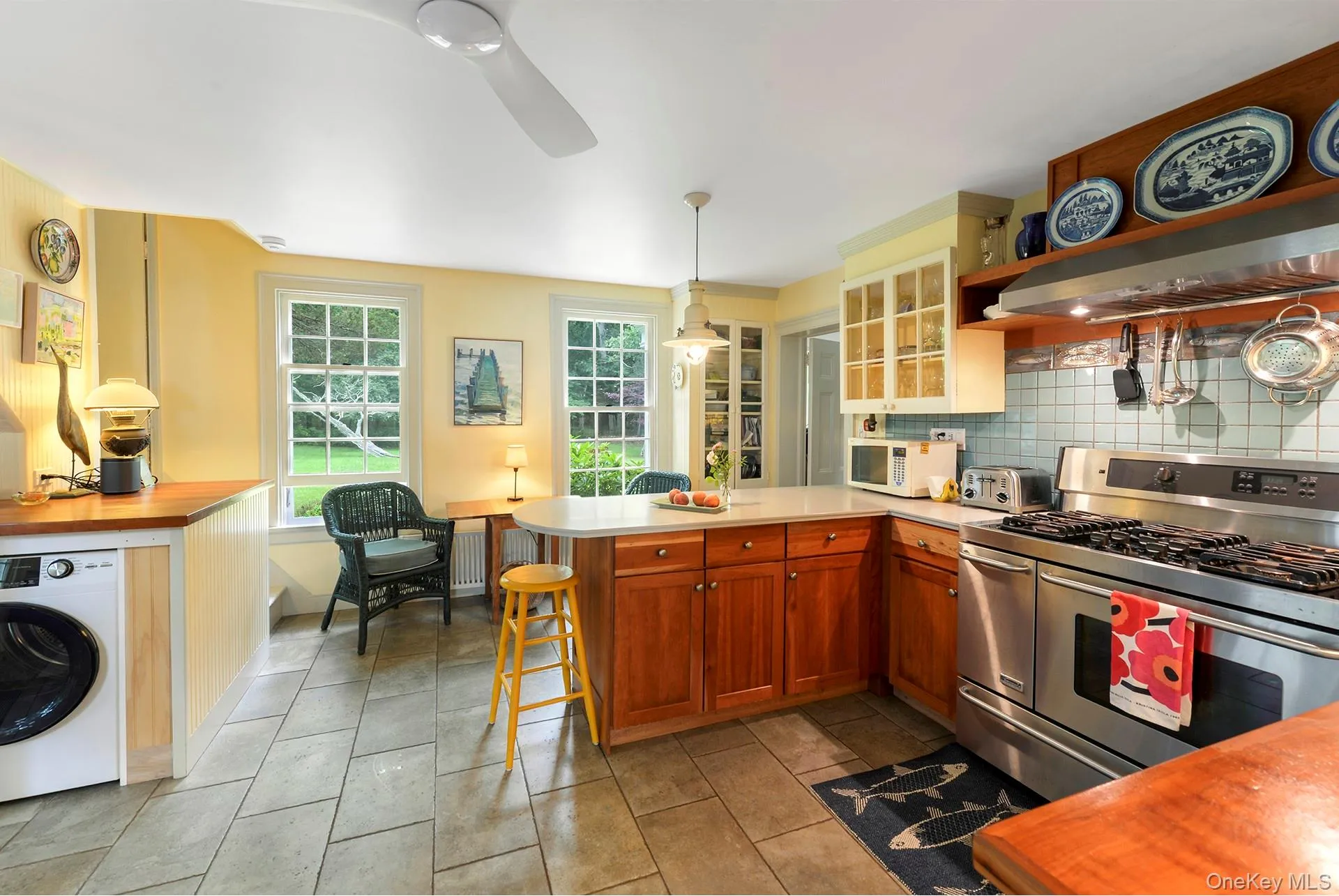 Kitchen featuring range with two ovens, washer / dryer,microwave, custom exhaust hood, and a peninsula Kitchen featuring range with two ovens, washer / dryer,microwave, custom exhaust hood, and a peninsula