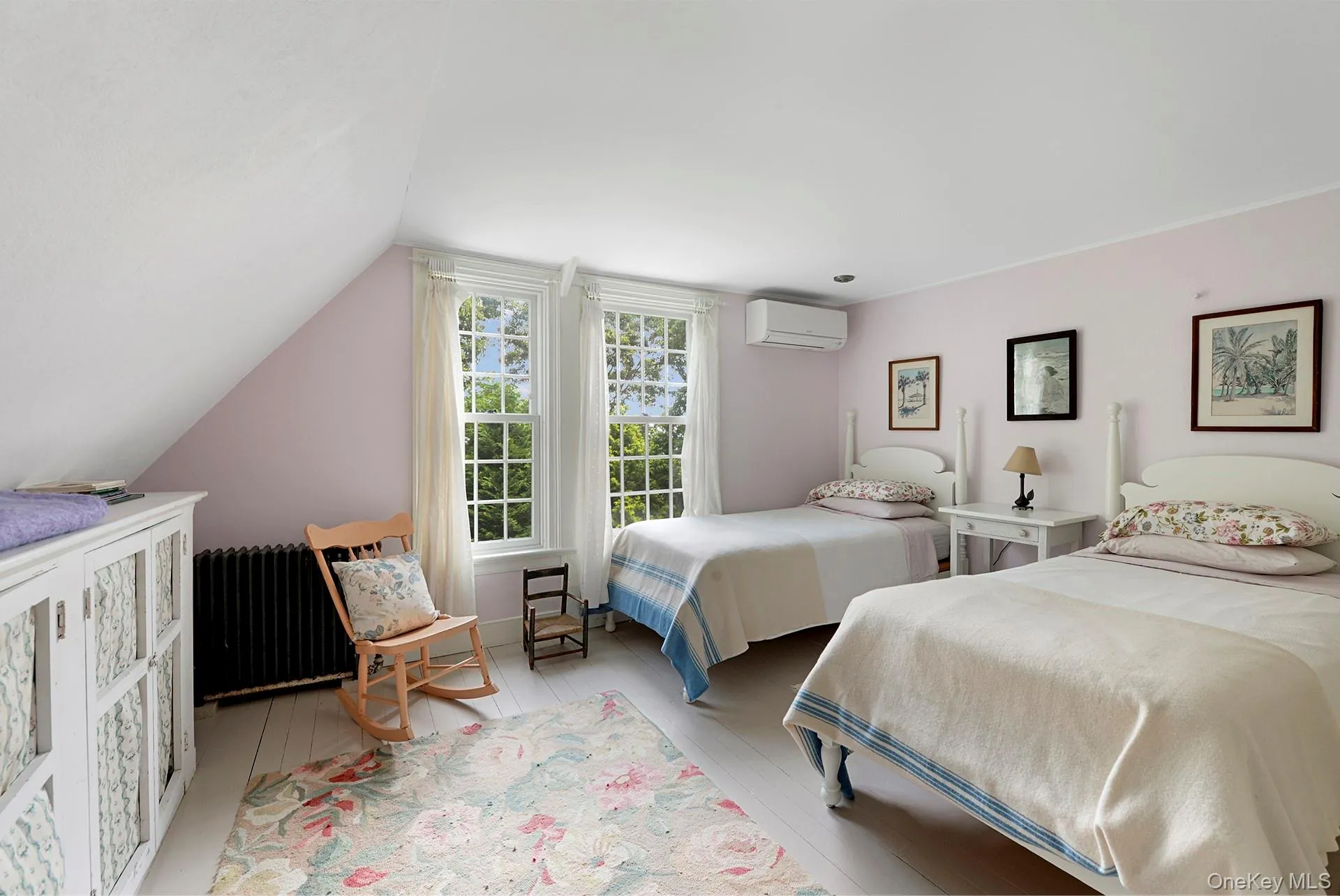 Bedroom with a wall mounted AC, radiator heating unit, vaulted ceiling, and light wood-style floors Bedroom with a wall mounted AC, radiator heating unit, vaulted ceiling, and light wood-style floors