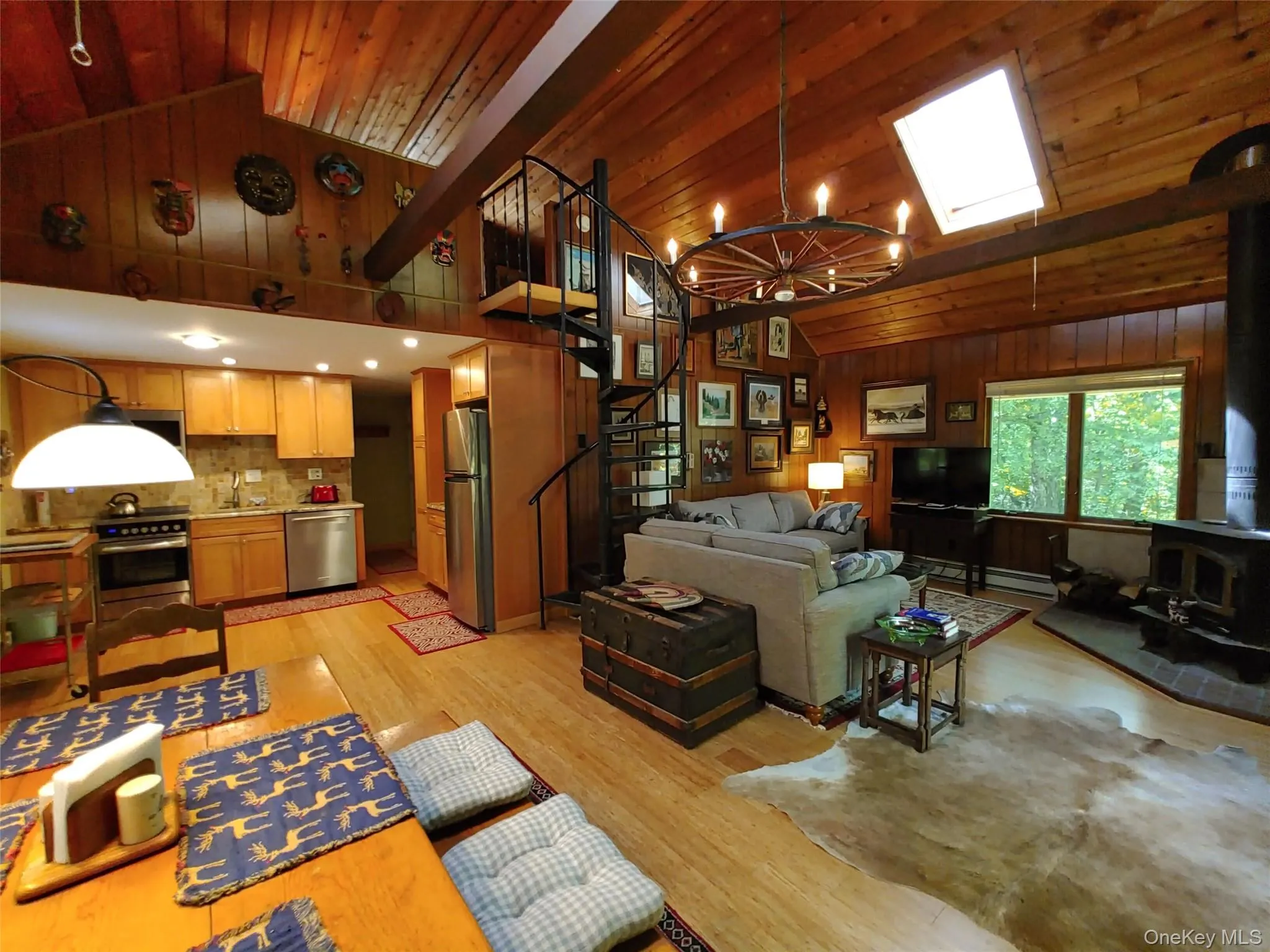 Living room with a wood stove, a chandelier, stairs, wooden walls, and bamboo plank floors Living room with a wood stove, a chandelier, stairs, wooden walls, and bamboo plank floors